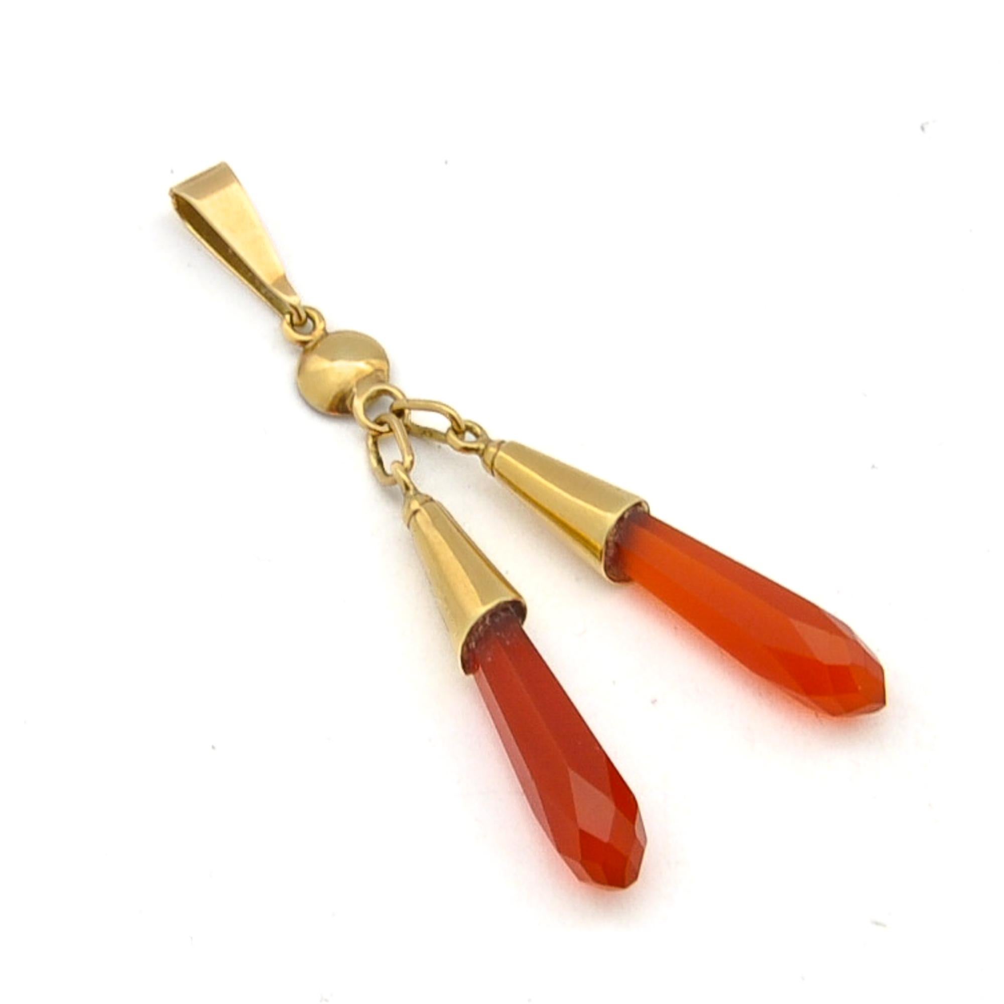 This gold pendant is set with two beautiful hexagon pointed carnelian crystals. The translucent and clear red orangish faceted carnelian stones are set in gold caps and swing freely. The two carnelian pendants are hold together by another bail above