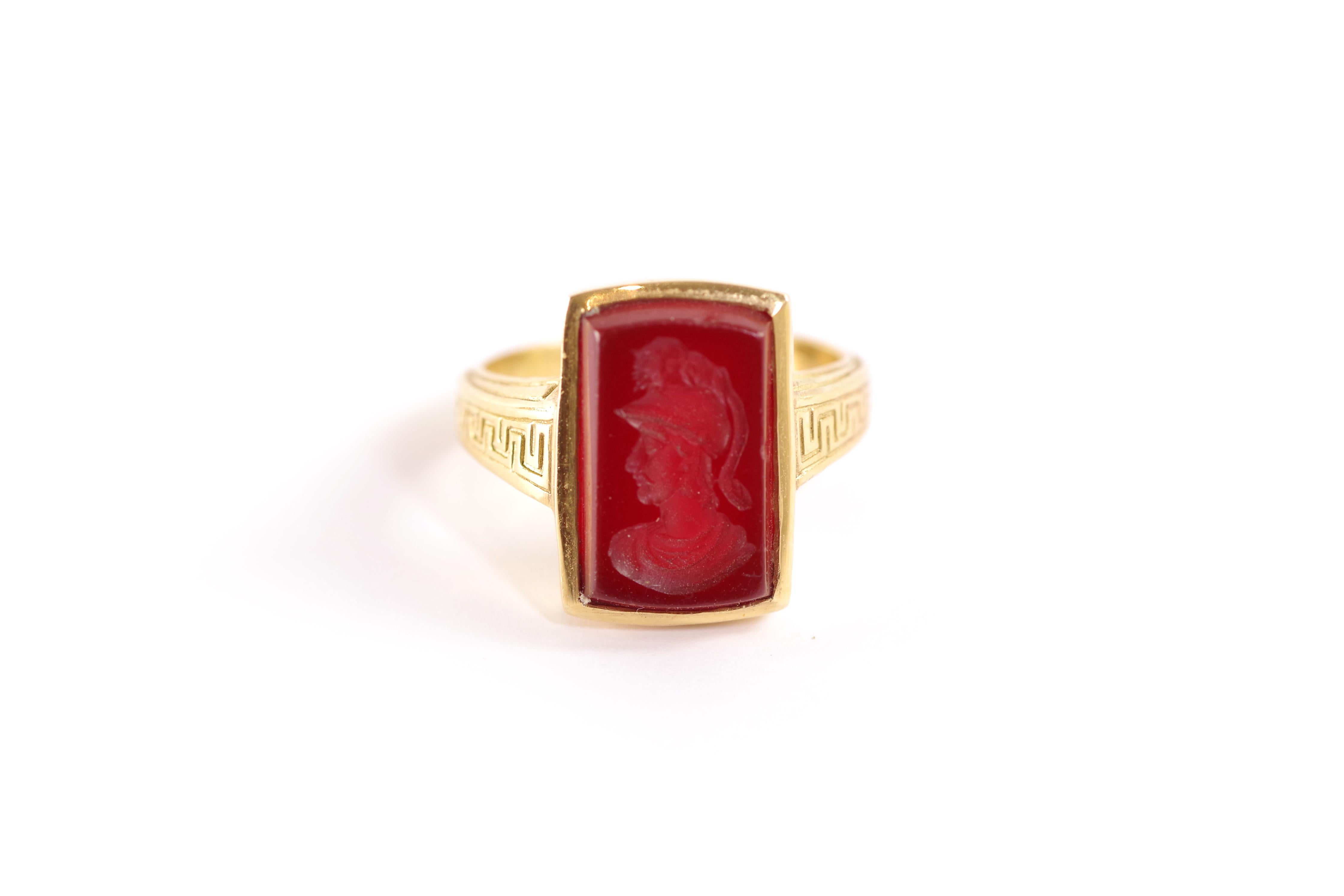 Carnelian intaglio ring in 18 karat yellow gold. Ring centred on a rectangular cornelian decorated with an intaglio depicting a Roman soldier in profile. The ring is finally decorated with Greek frieze on the shoulders. Vintage ring, circa 1990,