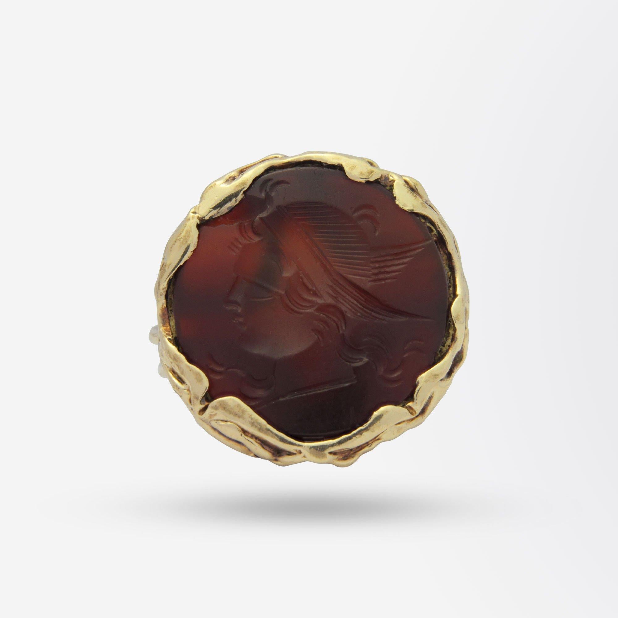 An unusual gents intaglio dress ring crafted from yellow gold and set with a carved deep red carnelian. The round twisted wire shank has split flow up shoulders which connect to the rubover set intaglio carnelian which depicts what appears to be a