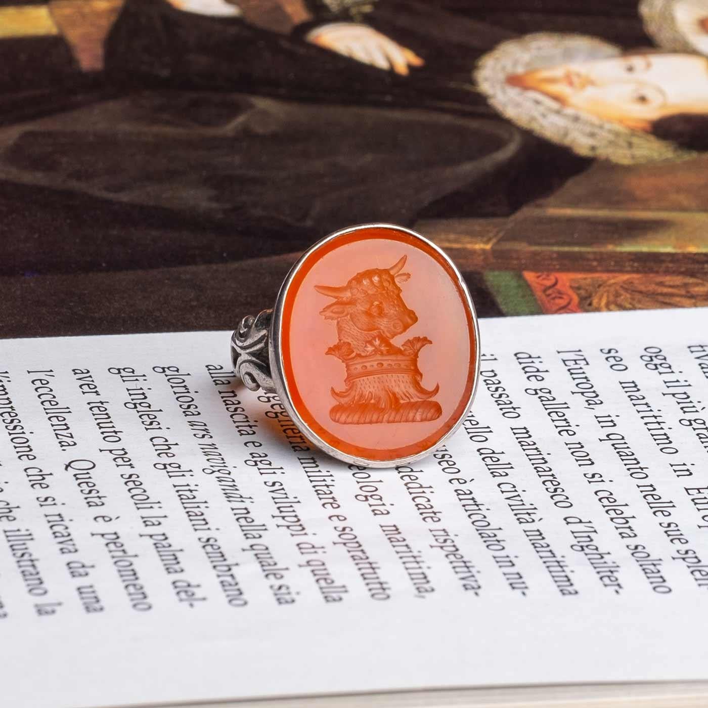 Carnelian intaglio ring set in silver depicting a bull.

Highlights
- Carnelian
- Silver ring setting

Measurements
- Length 1.9cm x Width 2.2cm
- Italian ring size 12 (size can be altered if required)