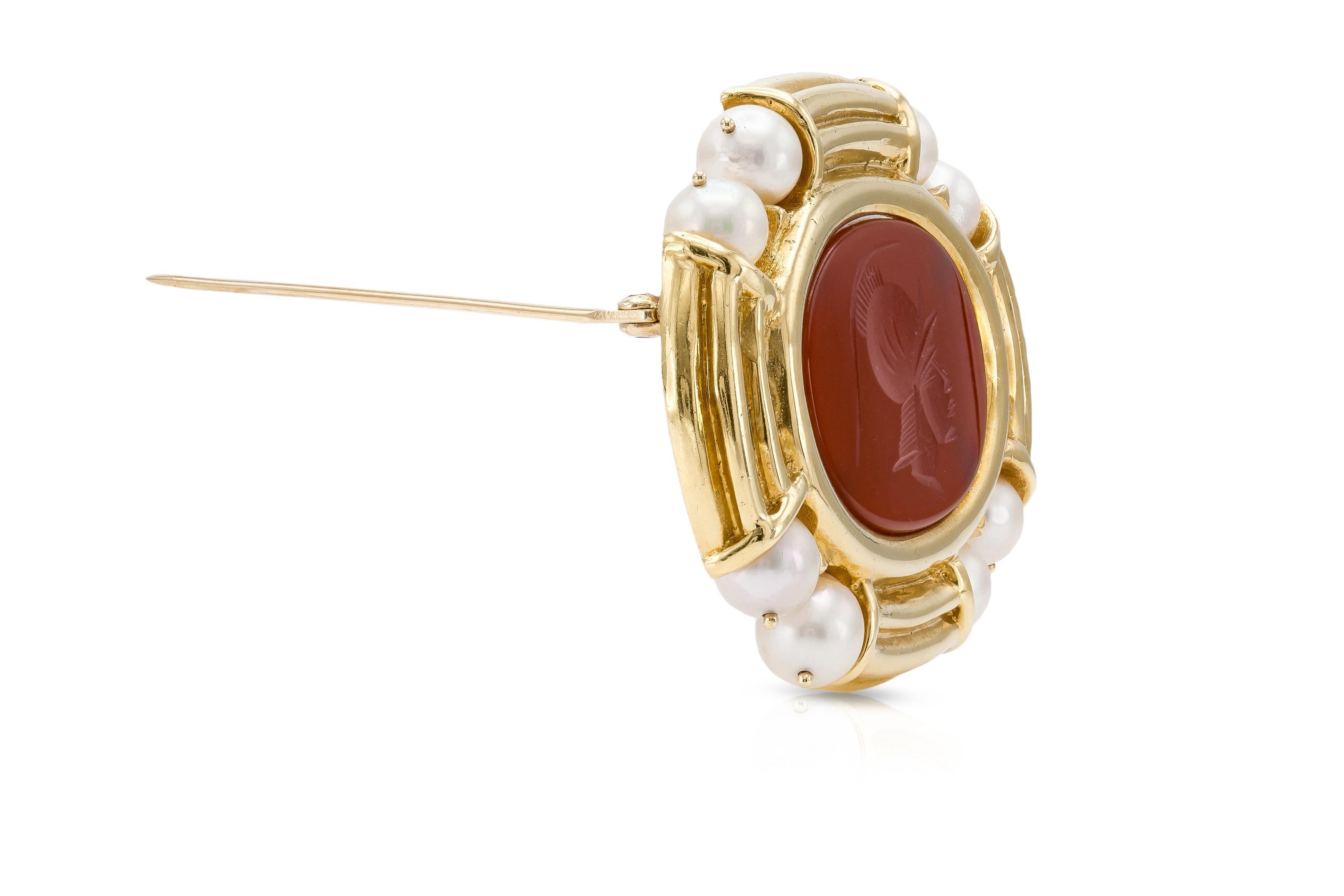 Finely crafted in 14k yellow gold with a Carnelian intaglio of a soldier.
The brooch features eight pearls.
2 x 1 1/2 inches