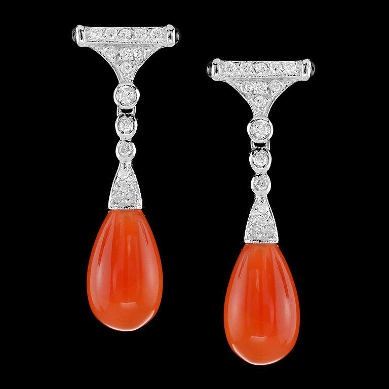Art Deco Style Drop Earrings crafted in 9K White Gold. A pair of good color Carnelian drops 12.05 ct. swing below a pair of sparkling diamonds set (32 pcs. 0.35 ct.) and small onyx (4 pcs. 0.24 ct.) on the side. They are fashionable and you could
