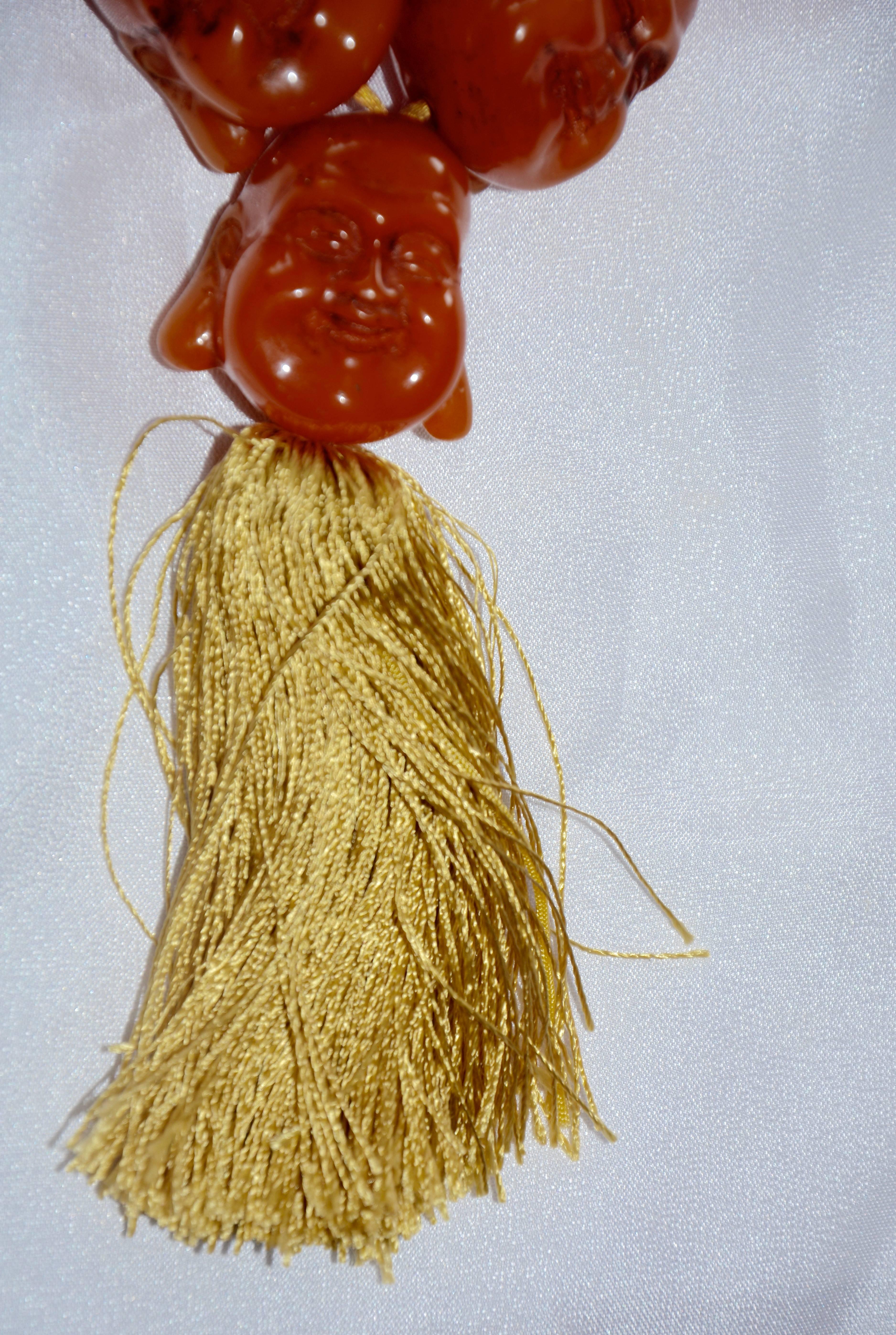 We are offering a statement necklace with 19 hand carved carnelian beads in the shape of smiling Buddha heads. A fringed tassel in gold strands completes the piece. This is a very unique collectible! Each head measures approximately 1.5inches long x