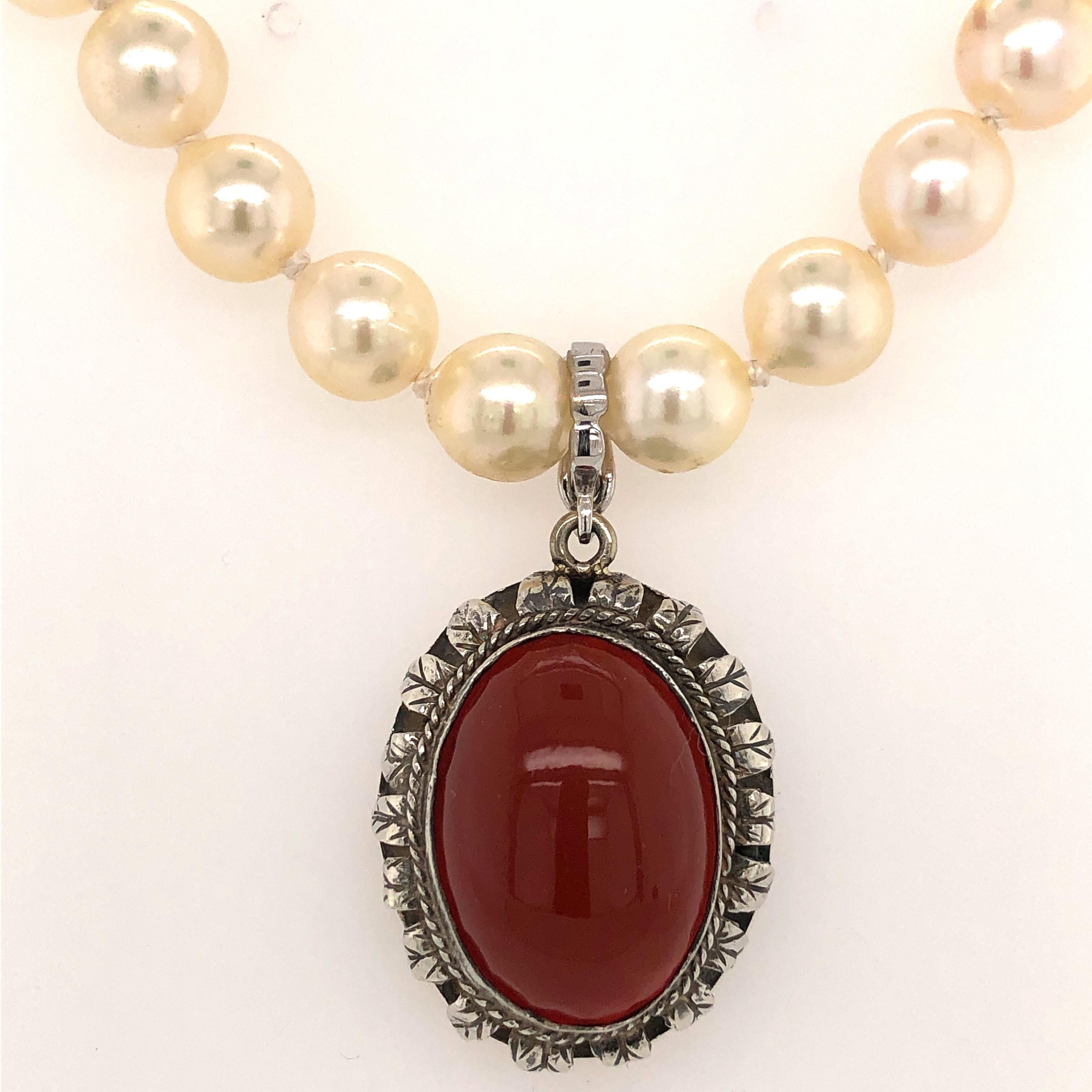 An earthy oval carnelian cabochon measuring 17 x 13 mm is bezel set in a frame of hand crafted sterling silver to create this vintage pendant.
Sitting pretty on a lustrous sixteen inch strand of pearls, this pendant is removable as an enhancer
