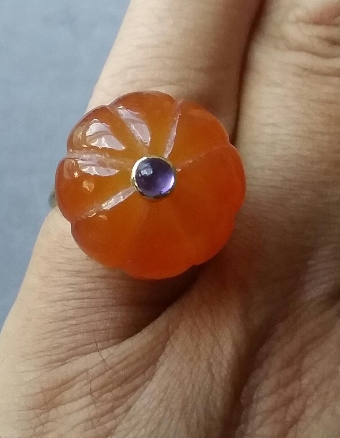 
Melon cut Carnelian Round Bead of 20 mm. in diameter and 16 mm. thick with in the center a round Amethyst cabochon of 4 mm. in diameter set in 14 kt yellow gold is mounted on top of a 14 Kt. yellow gold shank ( actual size #7, but can resize