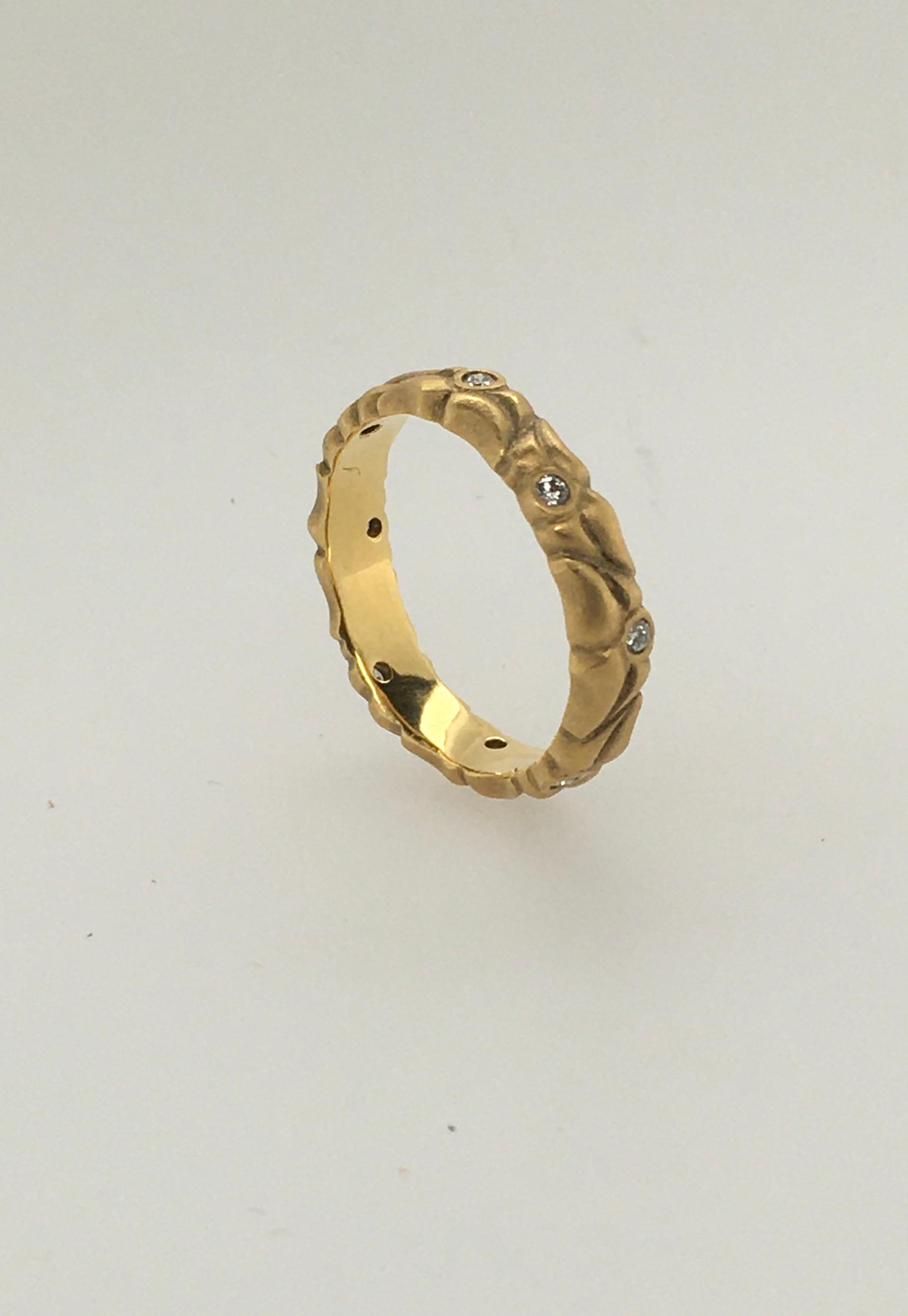 This distinctive ring is a 3.7 mm 18K yellow gold deeply carved leaf wedding band with eight  .12 CT diamonds.  The polished interior displays her imprint  