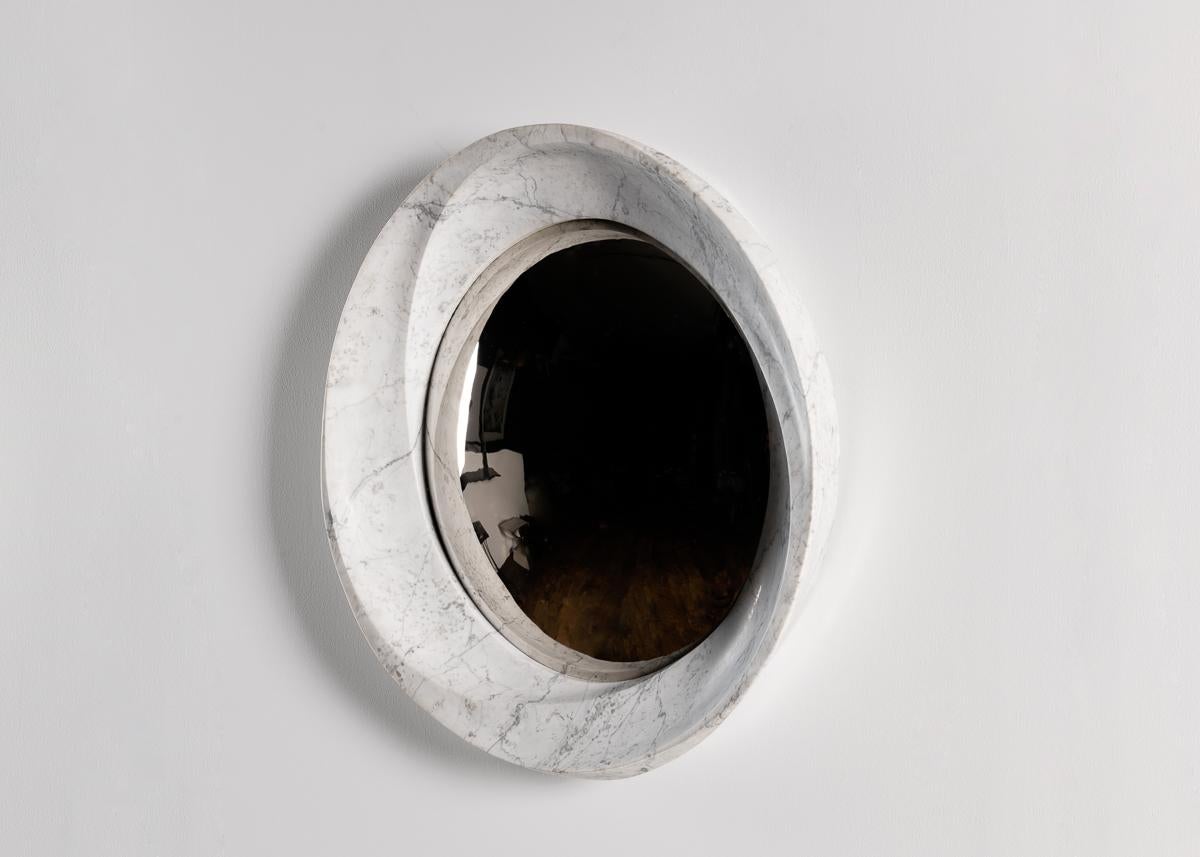 This sculptural mirror features a frame of lush marble with three inward spiraling ridges, the mutual vanishing point of which is a convex mirror of aluminum set within. The piece is one of the finest of a line of contemporary works that challenge