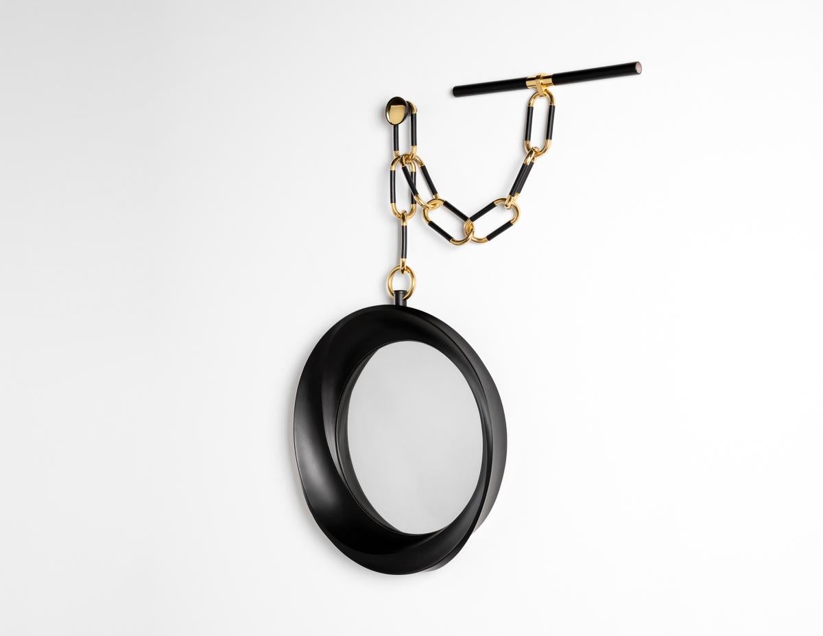 The ebonized mahogany frame of this mirror features three inward spiraling ridges, the mutual vanishing point of which is at the center of a convex mirror. Its hanging apparatus is inspired by the chain of a watch. The piece is one of the finest of