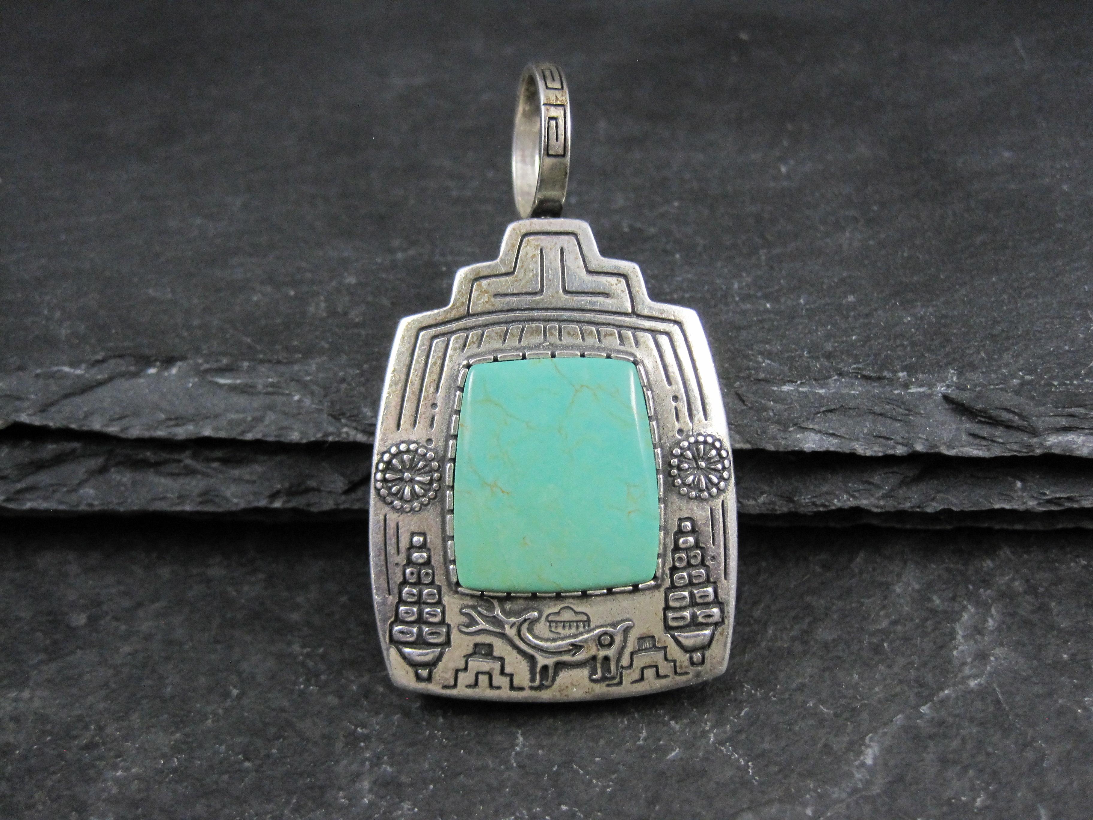 Questo splendido e pesante ciondolo reversibile è in argento sterling.
Un lato è caratterizzato da una bellissima gemma verde turchese con i disegni del raccolto. L'altra presenta una kachina e dei pueblo. 
Misure: 1 1/4 per 2 1/4 di pollice,