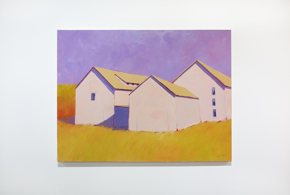 This colorful contemporary landscape painting by Carol Young features a warm, vibrant palette and captures three barns sitting in a yellow-gold field under a contrasting light violet sky. The barns cast stark, cool violet shadows. The painting is