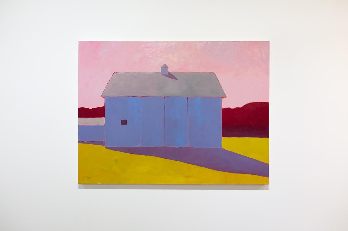 This colorful contemporary landscape painting by Carol Young features a warm, vibrant palette and captures a rural scene. A cool blue-violet barn sits in a yellow-gold field and casts a deep purple shadow beneath a pink sky. A red horizon line is