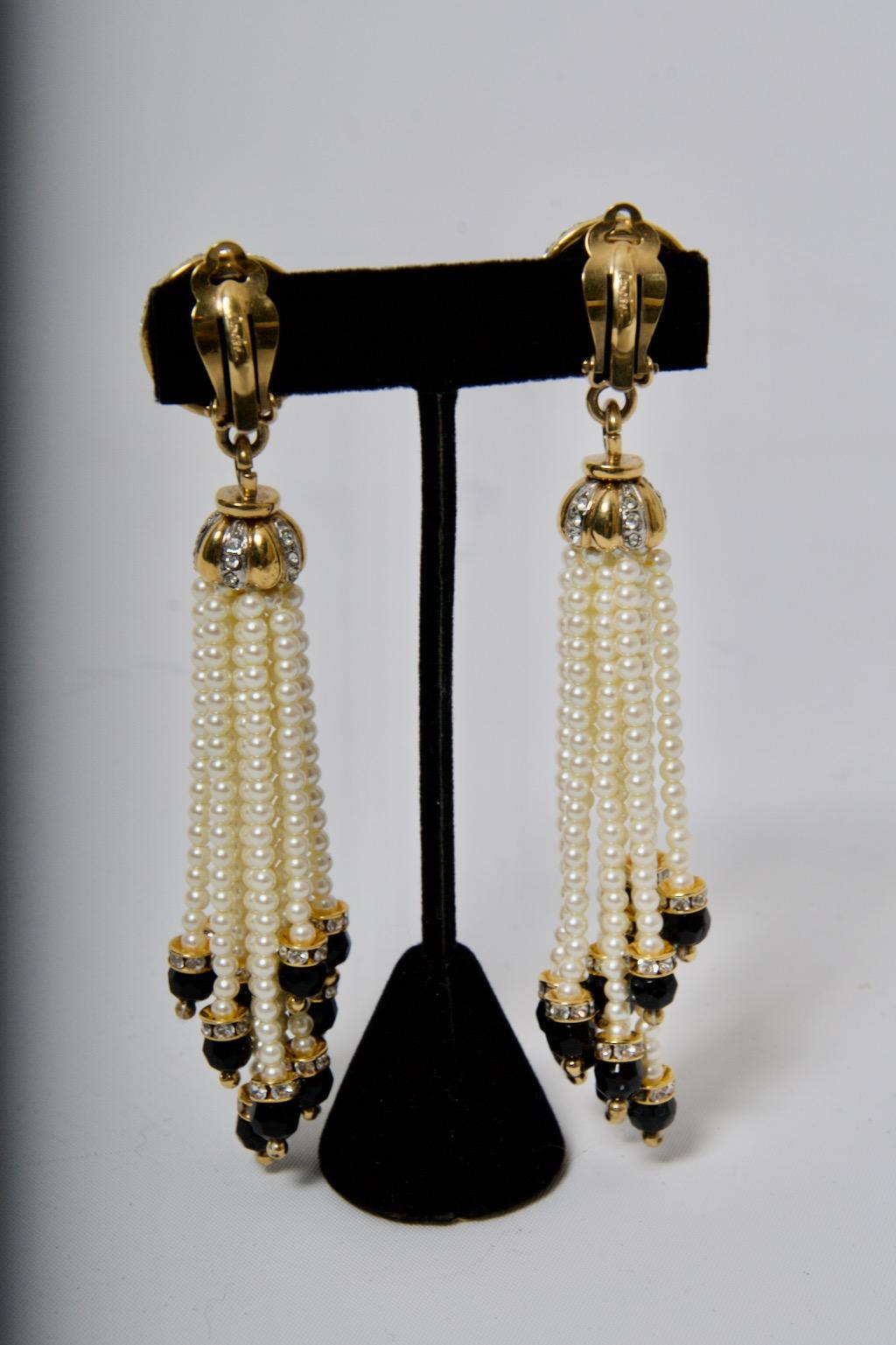 Dramatic, long Carolee clip-on chandelier earrings, the domed earpieces with pave rhinestones suspending by links a gold metal lobed crown capping twelve strands of small pearls, the strands of varying lengths. Each strand terminates with a