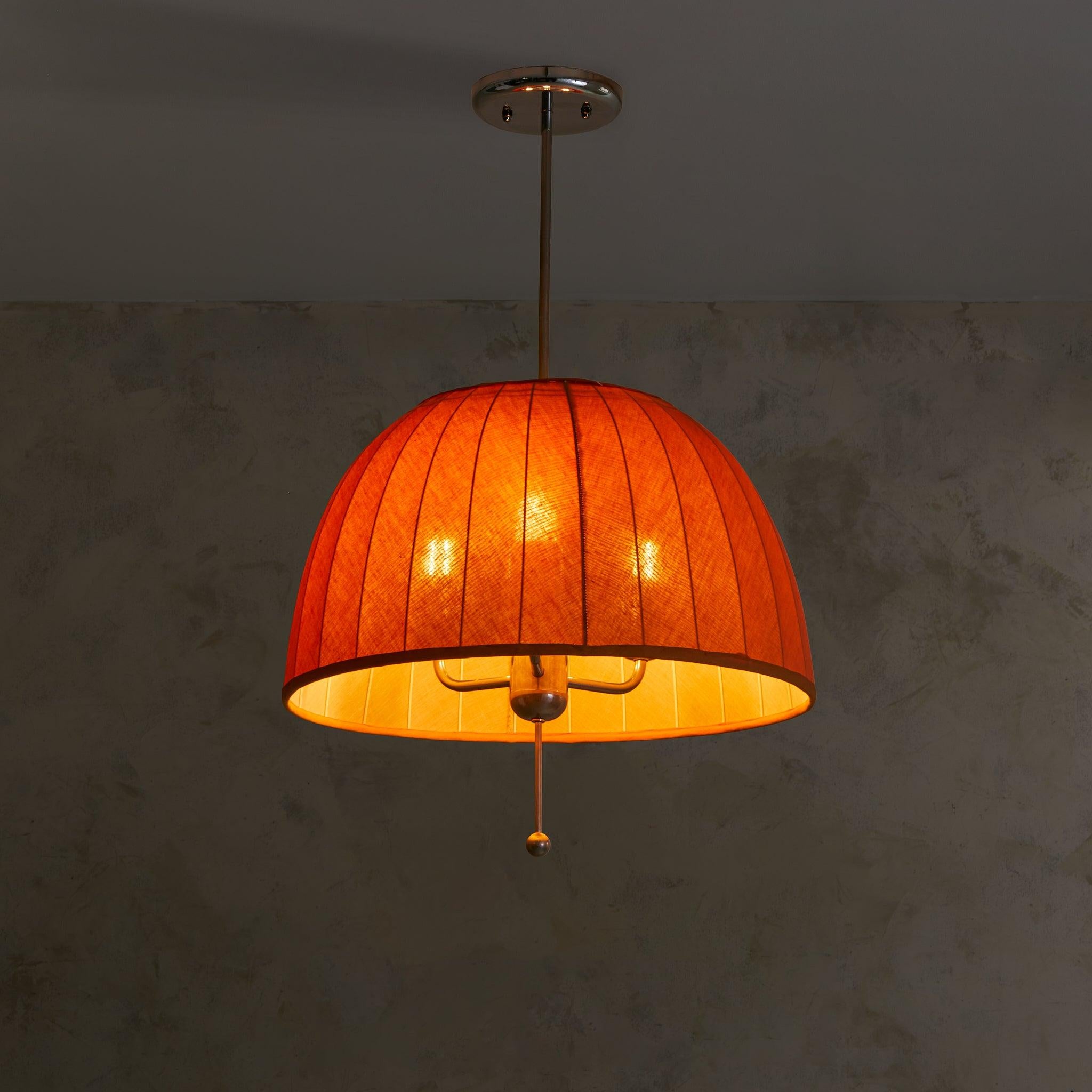 A rare Swedish pendant by Hans-Agne Jakobsson for AB Markaryd, model ‘Carolin’ T549/3. Designed in 1963, this softly domed fixture is clad in pleated, amber-toned textile, its glow warm and diffused when lit. Below, a brushed metal finial anchors