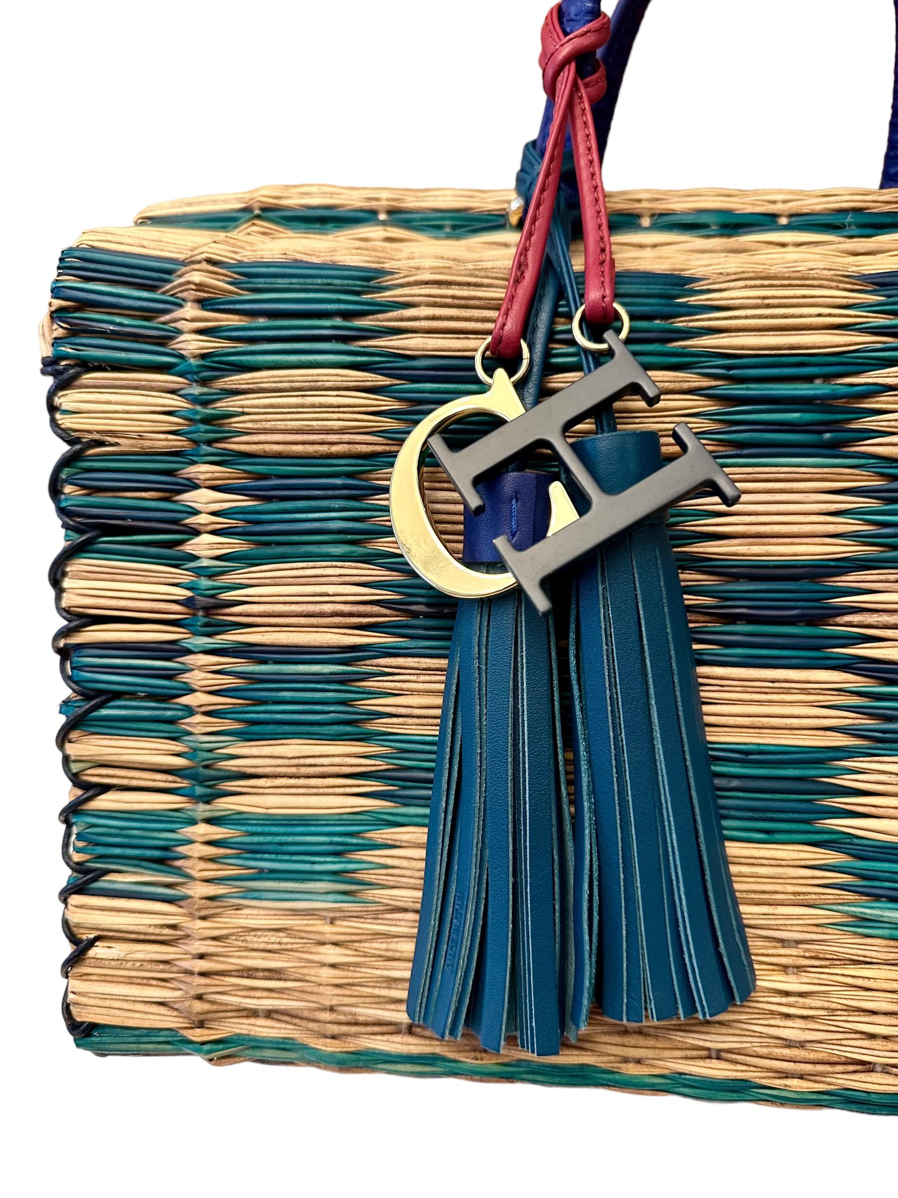 Diese gebrauchte Aveiro-Tasche wurde in Handarbeit aus gewebtem Raffiabast mit einem für Nordportugal typischen, farbenfrohen Muster gefertigt und mit einem Charme mit Carolinas Initialen und Lederquasten versehen. 
Sie hat Ledergriffe mit
