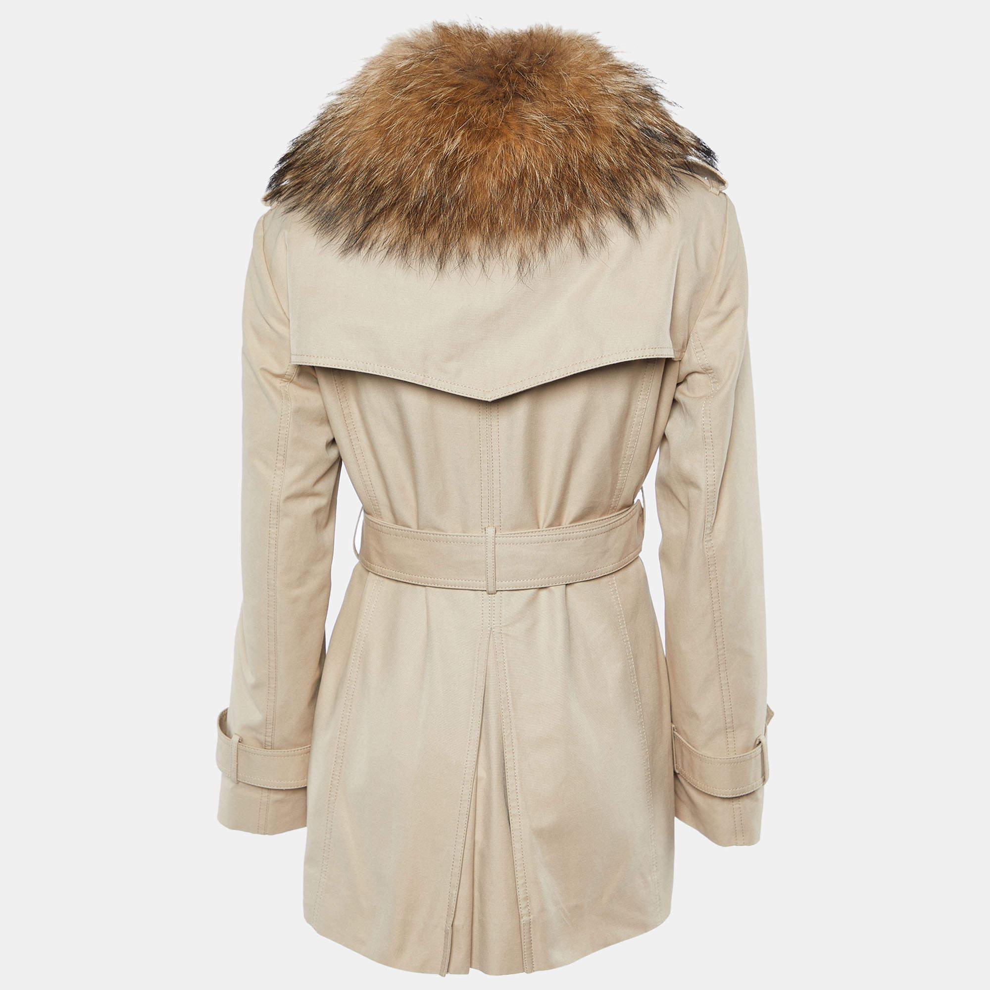 Start the winter season in style with this chic trench coat from the house of Carolina Herrera. It is designed in a versatile beige color and detailed with fur. It comes with button detailing and buckled waist belt for added style. Wear over a dress
