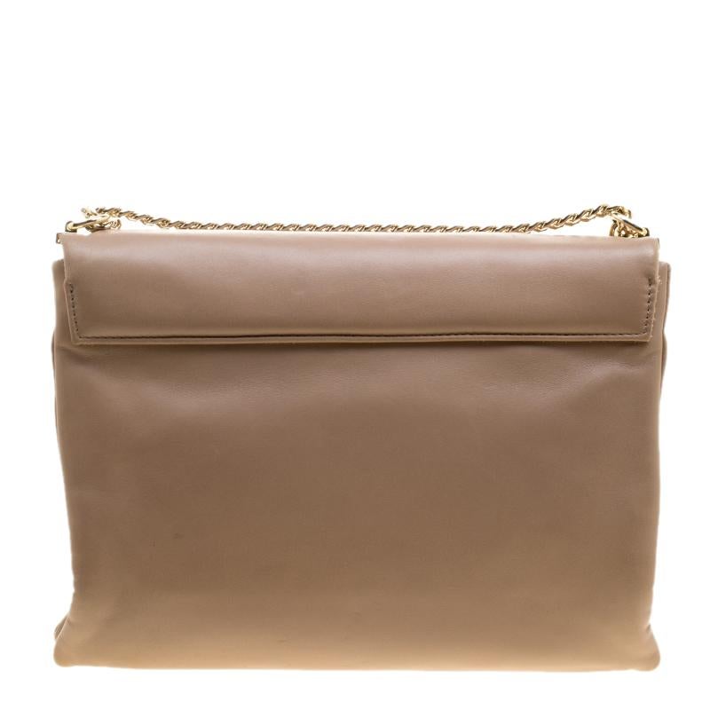 The minimalistic charm and elegance of this Carolina Herrera shoulder bag will surely steal your heart. This utterly subtle piece is crafted with soft beige-colored leather. It is designed in a flap style that opens to reveal a lush red interior