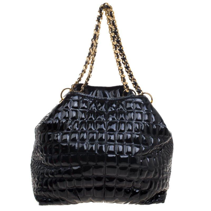 Embrace luxury with this rich black tote from the house of Carolina Herrera. The impeccable tote in patent leather bears an eye catching brand logo plaque at the front exterior. With an interwoven leather and chain strap, the tote opens to a wide