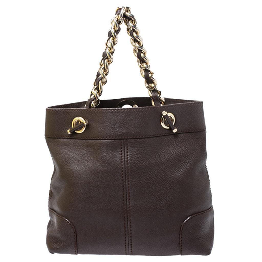 This luxe and chic tote by Carolina Herrera is crafted from brown leather and accented with gold-tone hardware. It is designed with interwoven chain link shoulder straps and a ball-shaped logo charm The large and open canvas-lined interior is ideal