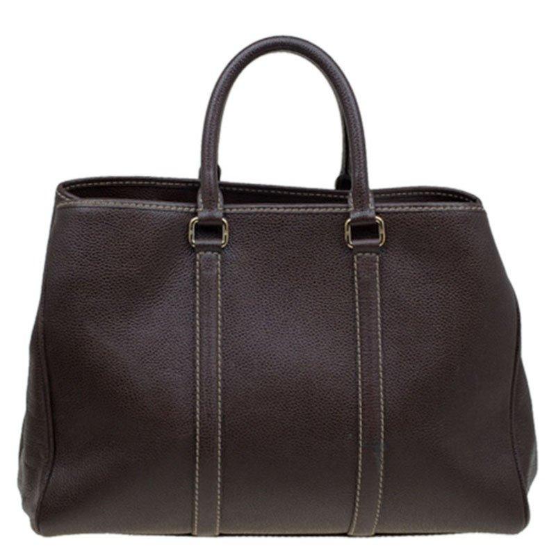 Carolina Herrara has been delivering functional, elegant designs. This dream tote from CH is made with monogrammed brown leather. It features gold-tone hardware, and two rolled handles. The zipped closure opens to a fabric-lined interior with two