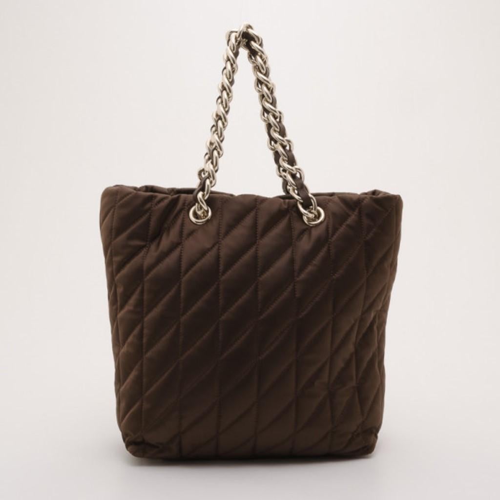 Enhance your look with this ultimate brown quilted tote by Carolina Herrera. Featuring a large silver ‘CH’ charm and double chain link shoulder straps, this bag will go with any casual and formal outfit. The large canvas lined interior features a