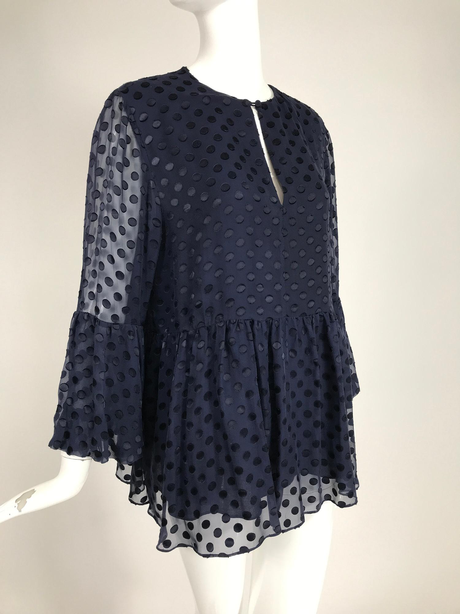 Carolina Herrera dark navy blue dot, voided velvet ruffle sleeve top. Only the dots have a silky velvety nap, the other areas of the fabric are sheer. Pull on top has a front neck vent, empire waist with gathered skirt below. Th long sleeves have