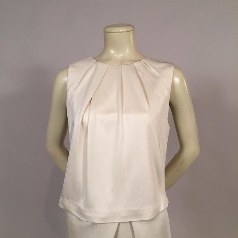 Ivory silk jersey drapes from the neckline of this one piece dress designed by Carolina Herrera. The draping continues from the waistline to the hem of the skirt creating a casual but classy look. Add some jewelry to change this dress into a more