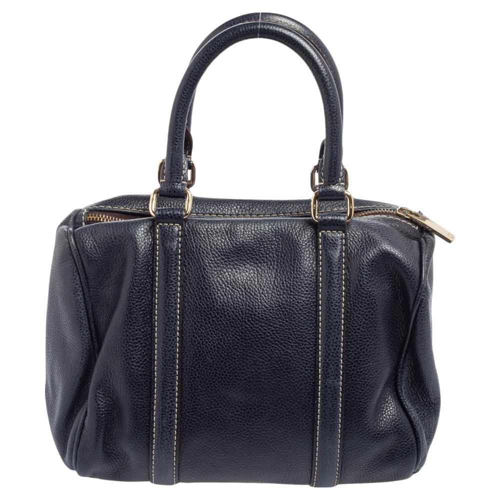 This Andy Boston bag by Carolina Herrera comes crafted from navy blue leather and is styled with contrast stitching and the CH logo. It features a top zip closure, two handles, and a spacious fabric interior to house your essentials. This bag is a