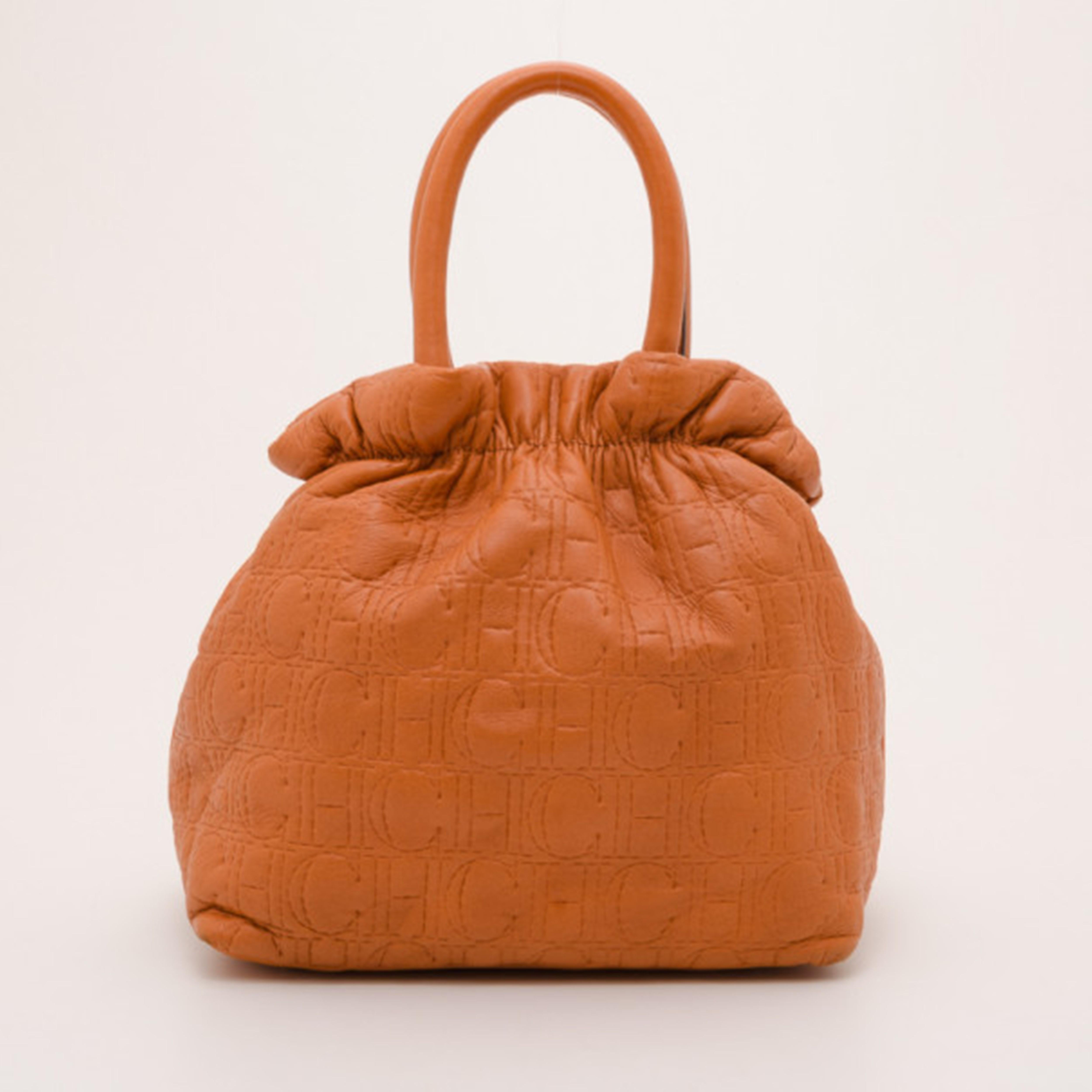 Look fabulous while carrying all your essentials in this elegantly shaped orange pleated bag by Carolina Herrera. With an exterior made from stunning orange CH stitched leather, this lovely bag features a top pleating design, a large CH HC charm and