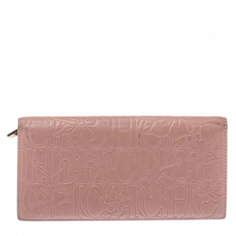 From Carolina Herrera comes this wallet that looks ready to assist your great style. It is crafted from pink leather and designed with floral and signature embossing all over. It opens to a leather and fabric interior that houses a zip pocket and