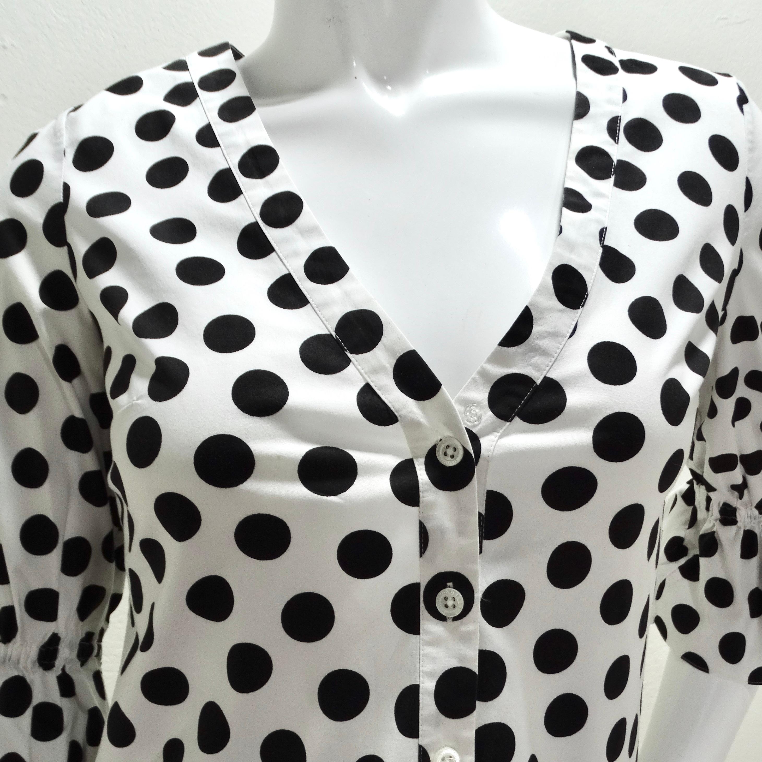 The Carolina Herrera Polka Dot Blouse is a timeless and chic addition to any wardrobe, perfect for adding a touch of playful elegance to your look. Crafted in a classic black and white polka dot pattern, this blouse exudes sophistication and