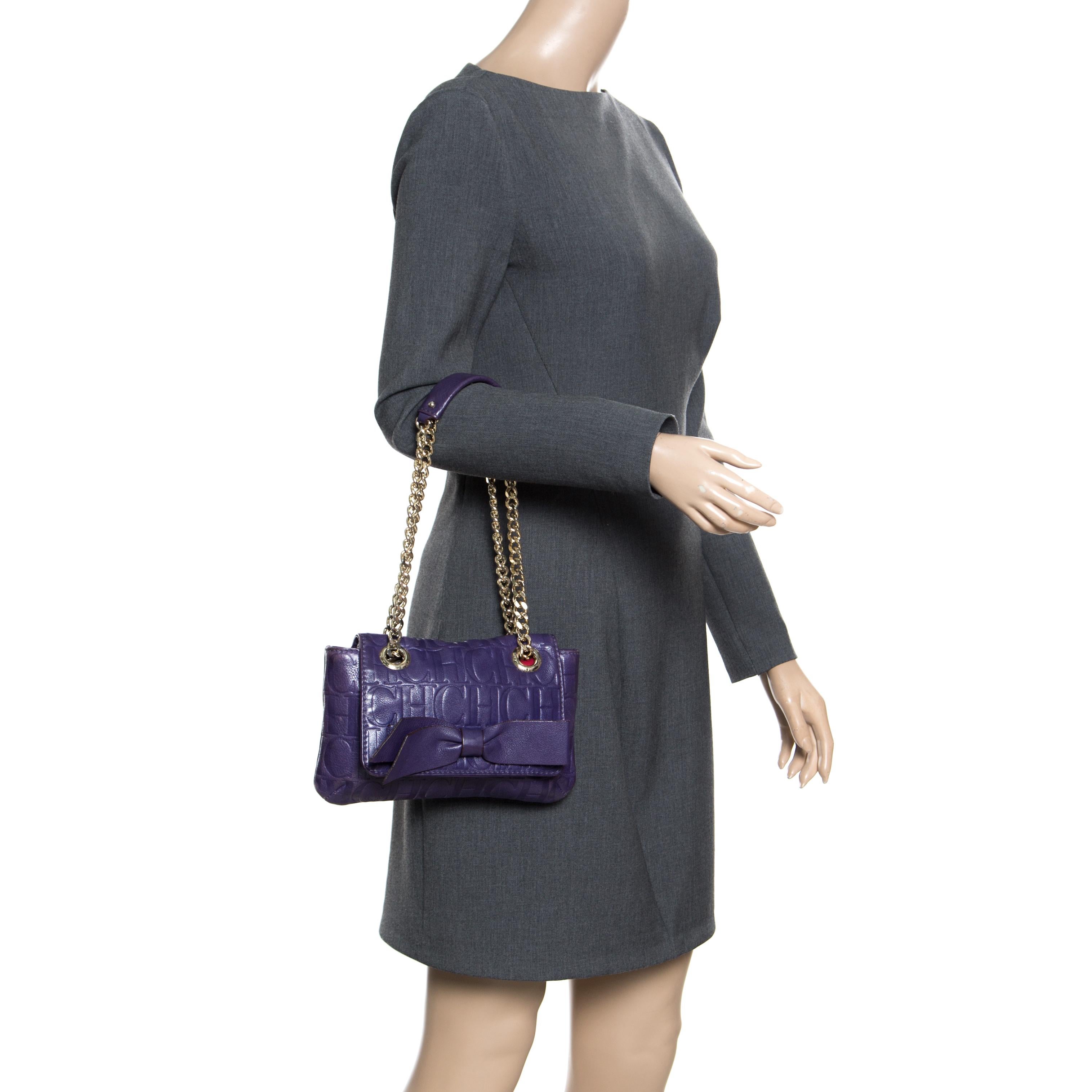 This Audrey bag from Carolina Herrera is styled with a bow detail on the front. It is crafted with signature monogram leather in a pretty purple color and a flap top that leads to a fabric-lined interior with a side zip pocket. The bag also features