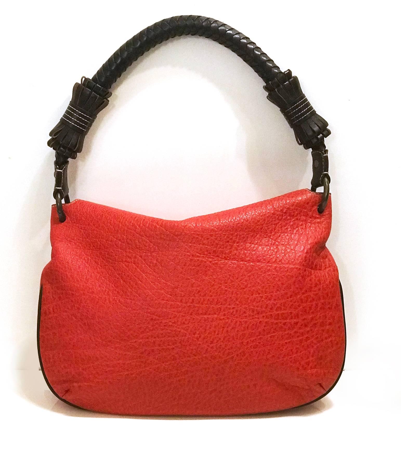 Impressive red hobo bag by Carolina Herrera, with a thick brown braided leather strap.
On the front of the bag the CHHC logo is printed in gold. The inside lining is brown with logo pattern and has a pocket with zip.
Strap is 56cm long.