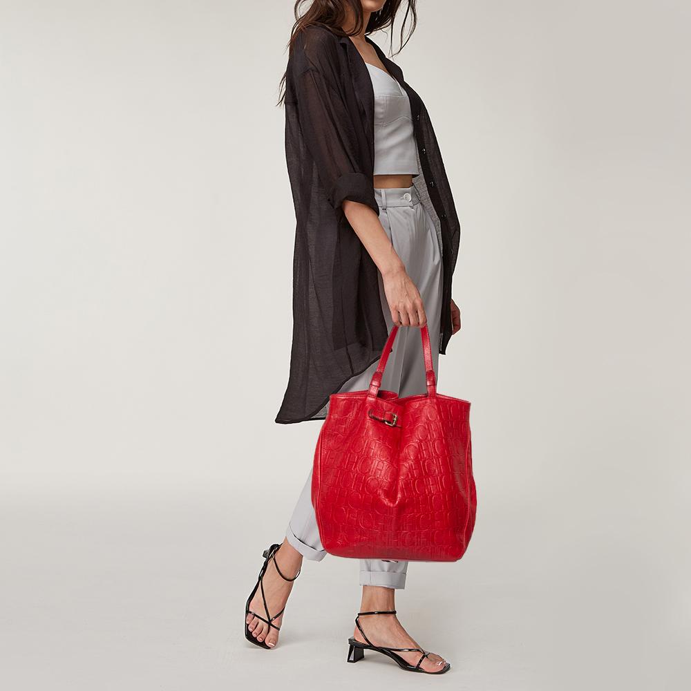 This stunning tote by Carolina Herrera is a must-have. Crafted from the brand's signature monogram leather, it comes in a red hue. It is equipped with a spacious interior and two handles. It is functional, durable, and has a relaxed