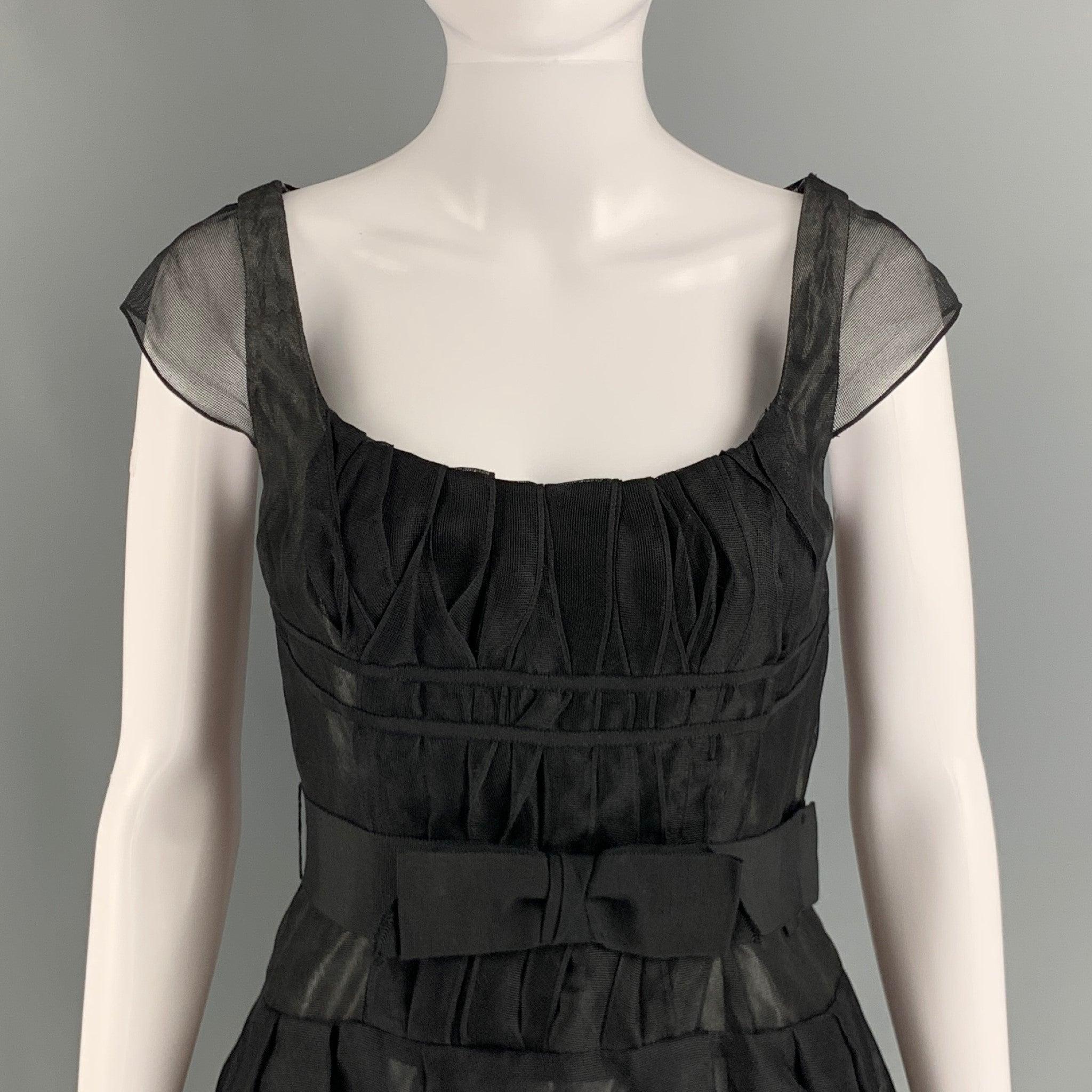 CAROLINA HERRERA A-line knee high dress comes in black silk tulle woven material and half invisible zipper closure at center back featuring cap sleeve, see through style and bow belted at center front of waistband. Made in USA.Excellent Pre-Owned