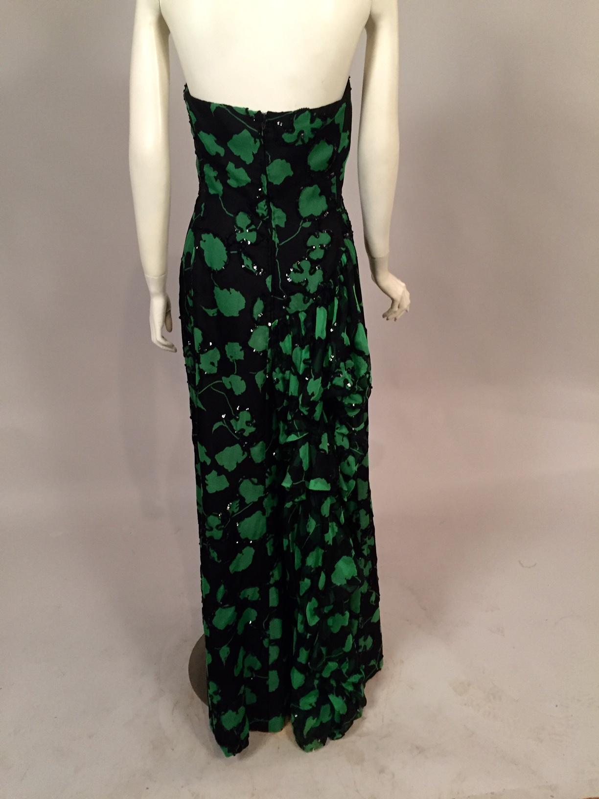 A strapless black silk organza evening dress is printed with a lovely meandering green vine pattern. Some, but not all, of this vine is outline beaded with black  sequins. The dress has a boned bodice and a center back zipper. It is fully lined with