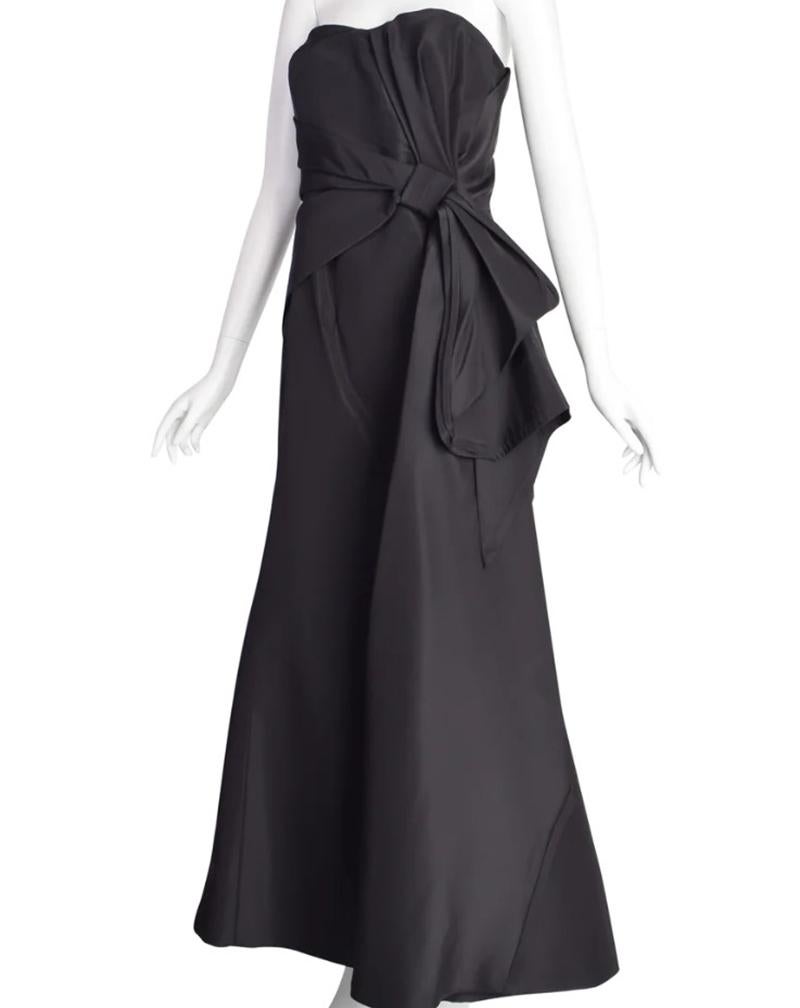 CAROLINA HERRERA

Breathtaking vintage dress by Carolina Herrera. This stunning evening gown comes in a sturdy black silk faille. Gathered bust line with inner padded cup and boned fitting. Drape at the high waistline that comes into a knot with an