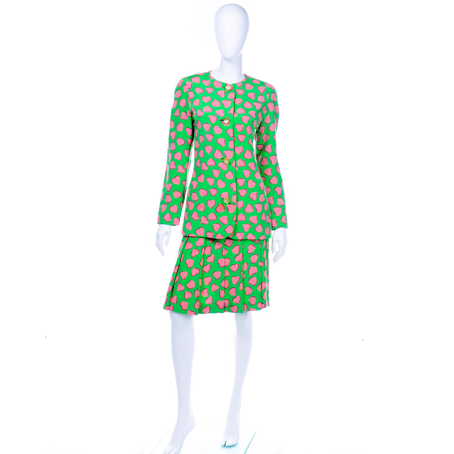 Dieser wunderbare Carolina Herrera Rock aus grüner Seide ist mit einem pinkfarbenen Herzmotiv bedruckt. Dieses tolle Outfit ist eine perfekte Alternative zum Tageskleid! Die kragenlose Jacke  hat abgerundete Schultern und lange, spitz zulaufende