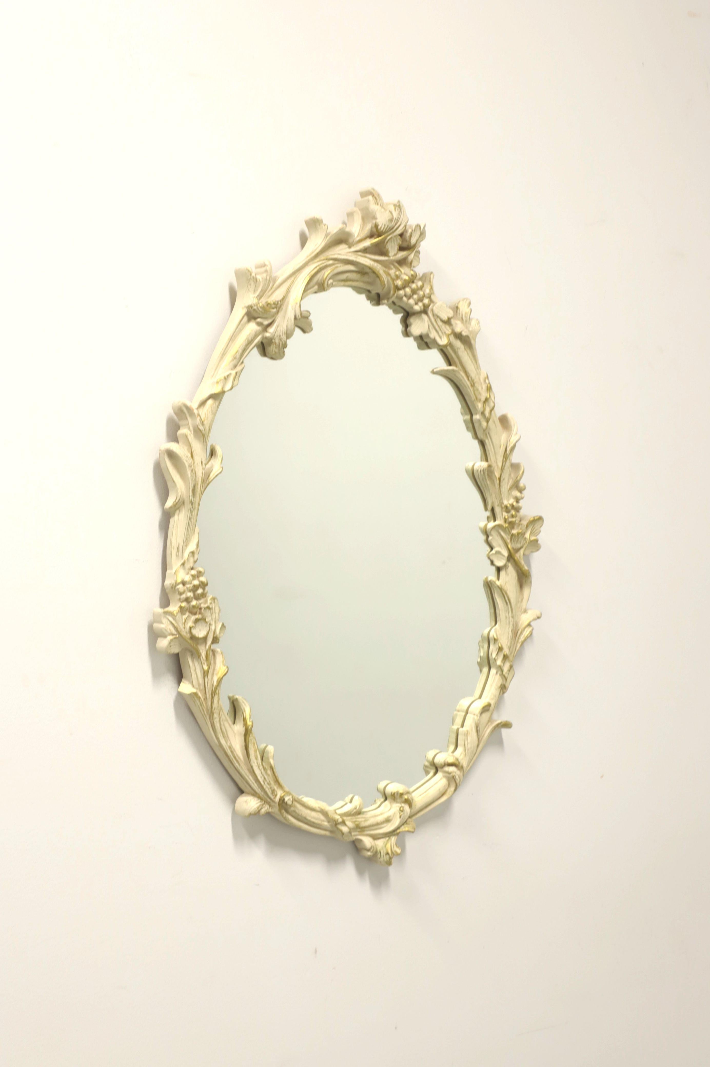 A French style wall mirror by Carolina Mirror. Mirrored glass and solid wood frame painted antique white. Features ornately carved frame with a floral motif. Made in North Carolina, USA, in the late 20th Century. 

Measures: 22.75 W 1.5 D 34.25 H,