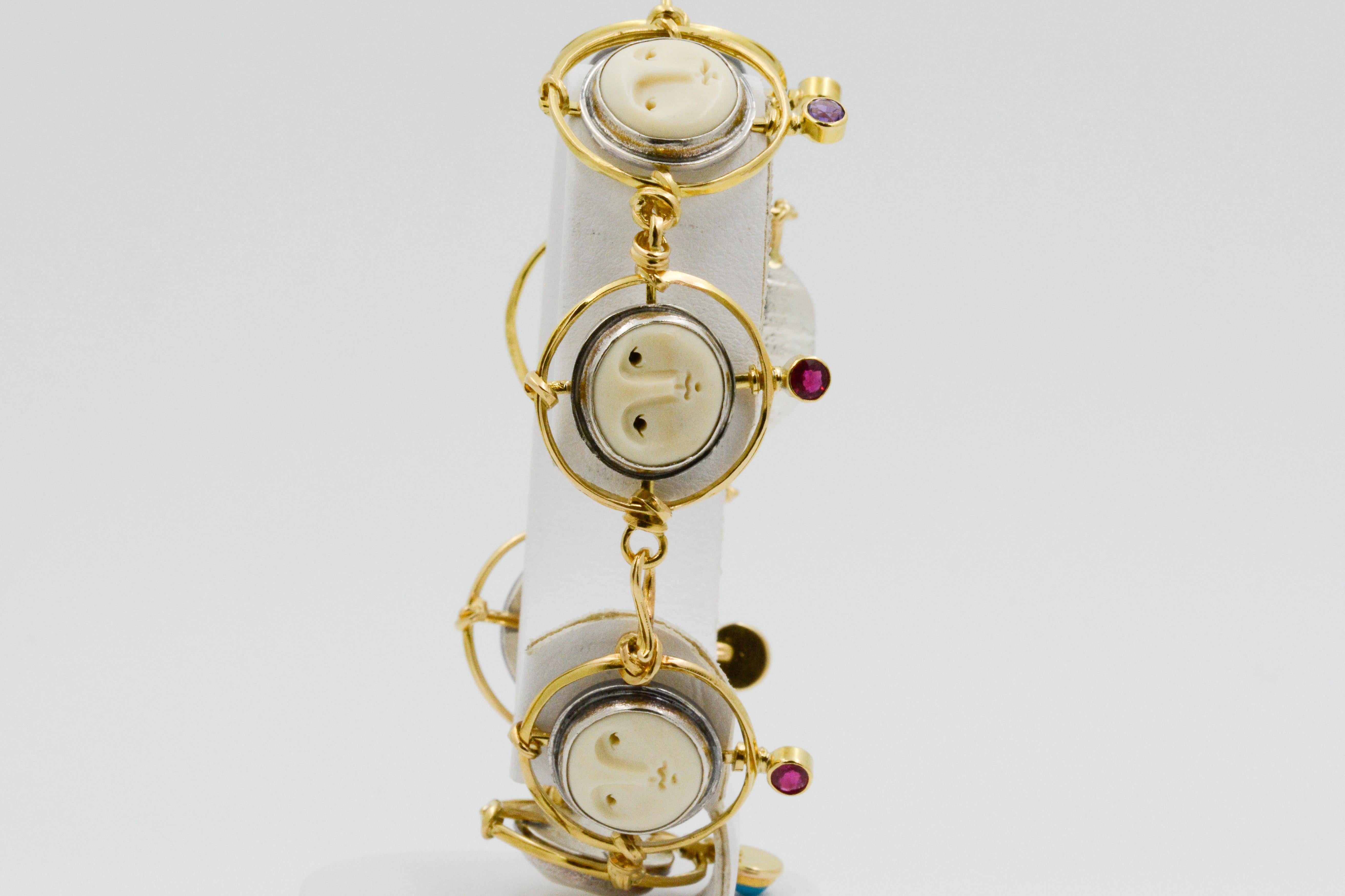 This unique arts and crafts Carolyn Morris Bach bracelet features a carved bone dog figure and six bone faces, accented by 18k yellow gold and sterling silver. At the bottom of each bone figure, surrounded by gold, are three bezel set round rubies