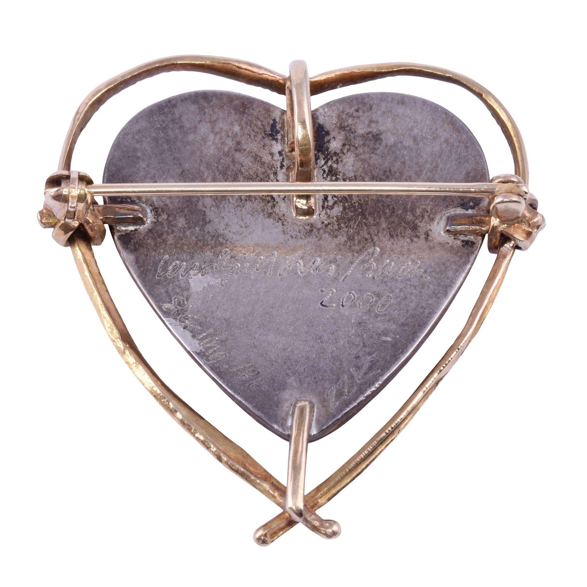 Estate Carolyn Morris Bach heart brooch or pendant, dated 2000. This brooch is crafted in 18-22 karat gold and sterling silver by Carolyn Morris Bach. The designer pin feature a heart shaped cut stone. The estate heart pin weighs 10.7 grams. [SJ