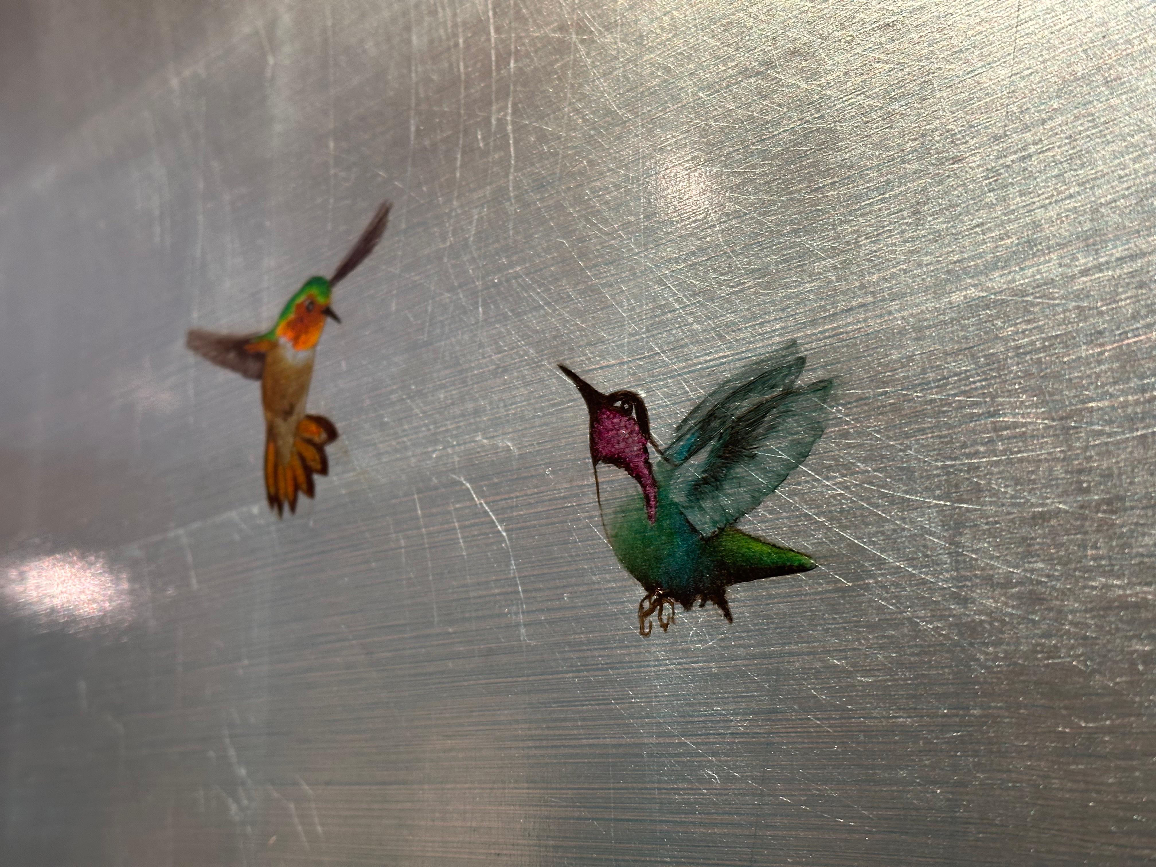 A wonderful composition of one of Reynolds’ most iconic subjects, hummingbirds. This piece depicts two multicolored hummingbirds mid-flight over a teal and silver reflecting pond. The deep green reeds add wonderful movement and contrast to the