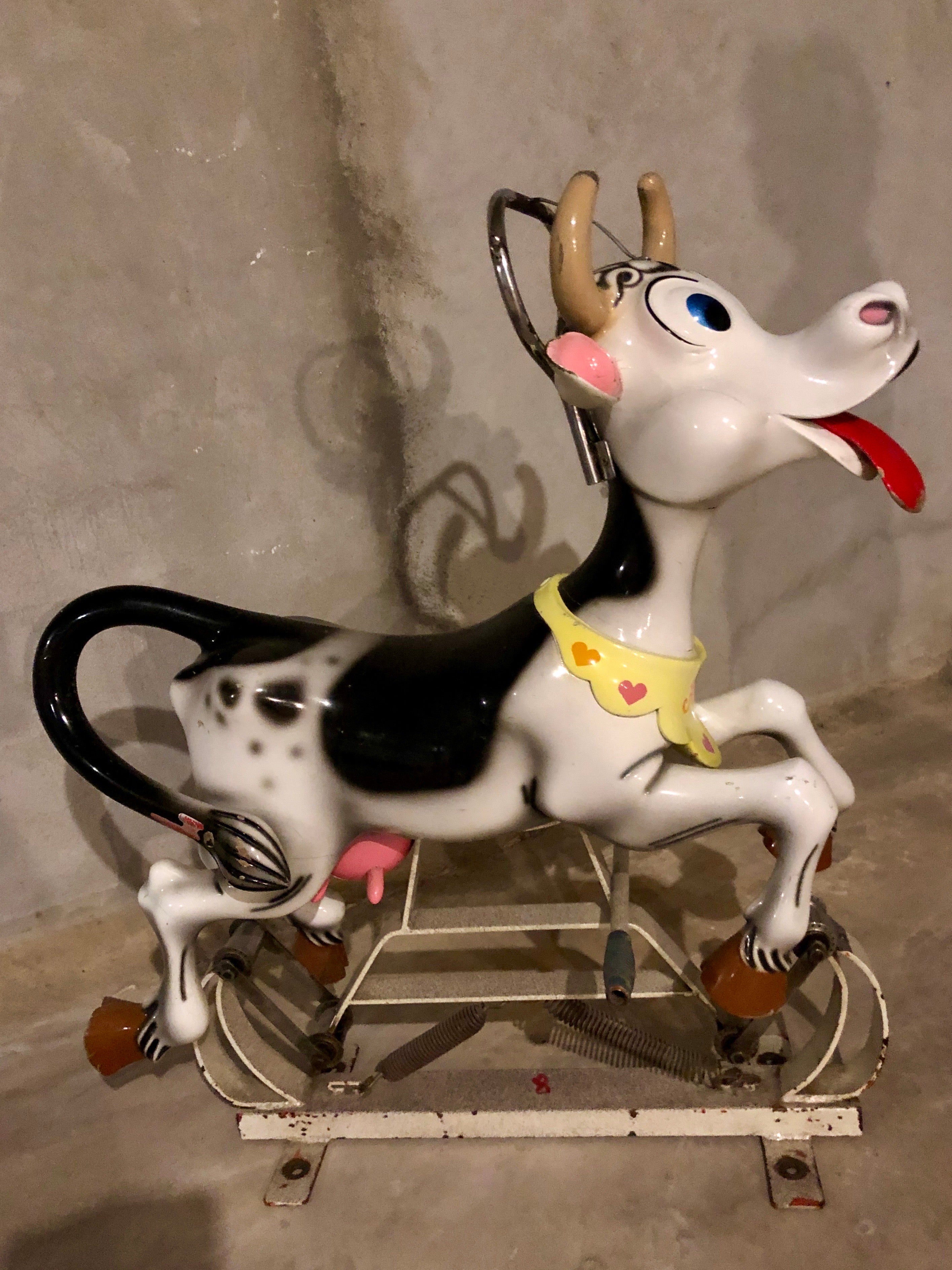 Smiling carousel cow by Bernard Kindt, 
a Belgian sculptor who was specialised in making wood carousel animals and animated cartoon characters. 
This carousel cow has the name Rosalie. 
A painted carved wood cartoon cow mounted on the original metal