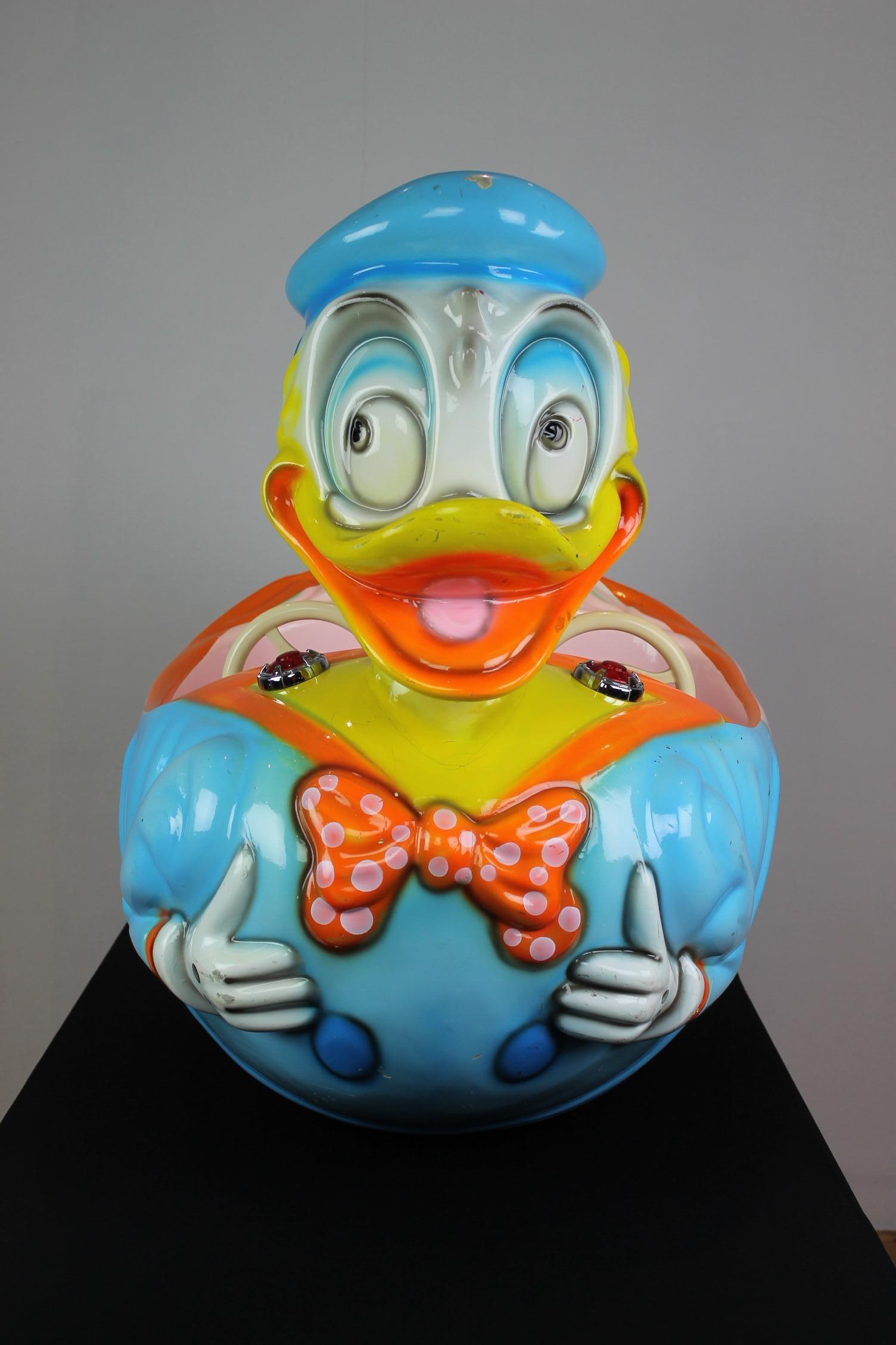 Donald Duck Fahrgeschäft oder Kinderfahrgeschäft. 
Ein Karussell Donald Duck in hellen Farben, die Sie lächeln macht. 
Es handelt sich um ein zweisitziges Kinderfahrgeschäft mit zwei Lenkrädern in Form von Donald Duck, der bekannten