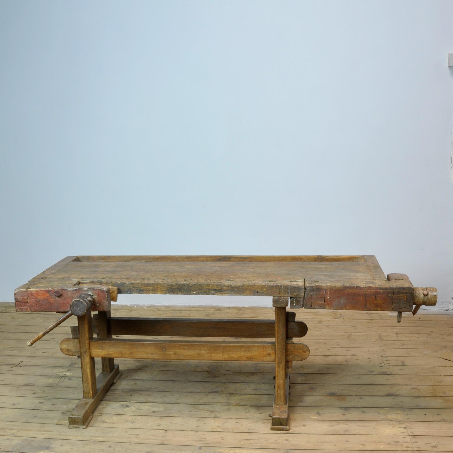 This antique workbench has two hand carved built-in wooden vice screws and a recessed tray where the carpenter would put his tools. It was manufactured circa 1900. Made from oak. Beautiful patina after years of intensive use. The workbench has been