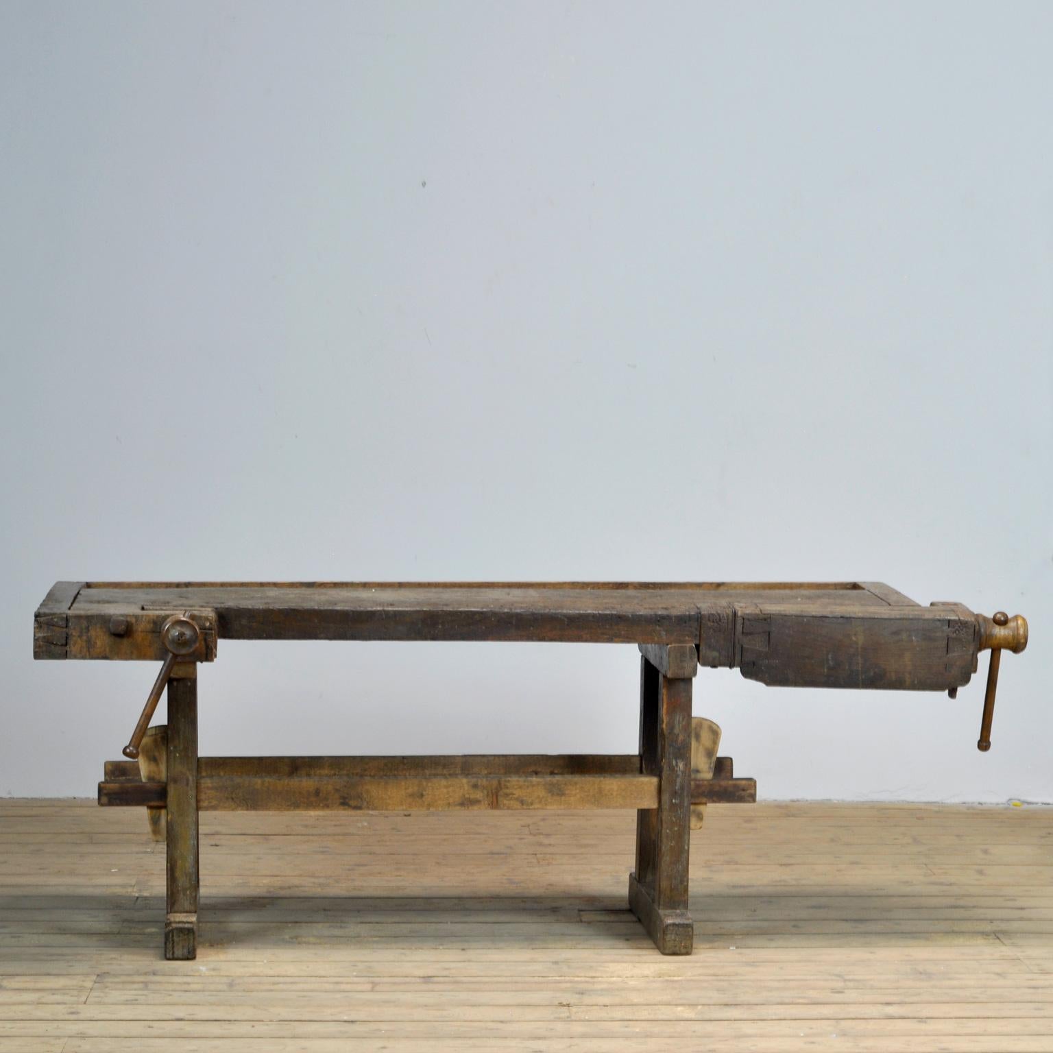 This antique workbench has two built-in wooden vices screws and a recessed tray where the carpenter would put his tools. It was manufactured, circa 1900. Made from oak. Beautiful patina after years of use. Really nice details in the construction.
