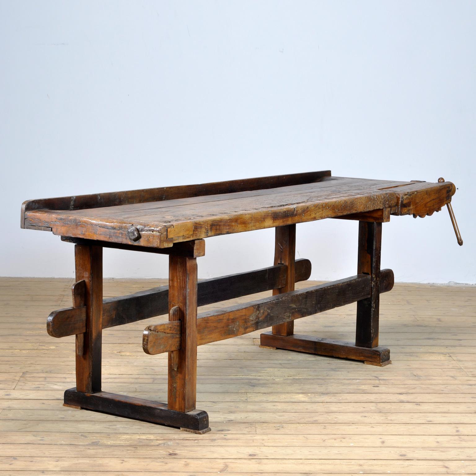 This antique workbench has a built-in wooden vice screw and a recessed tray where the carpenter would put his tools. It was manufactured circa 1900. Made from oak. Beautiful patina after years of intensive use. The workbench has been restored and