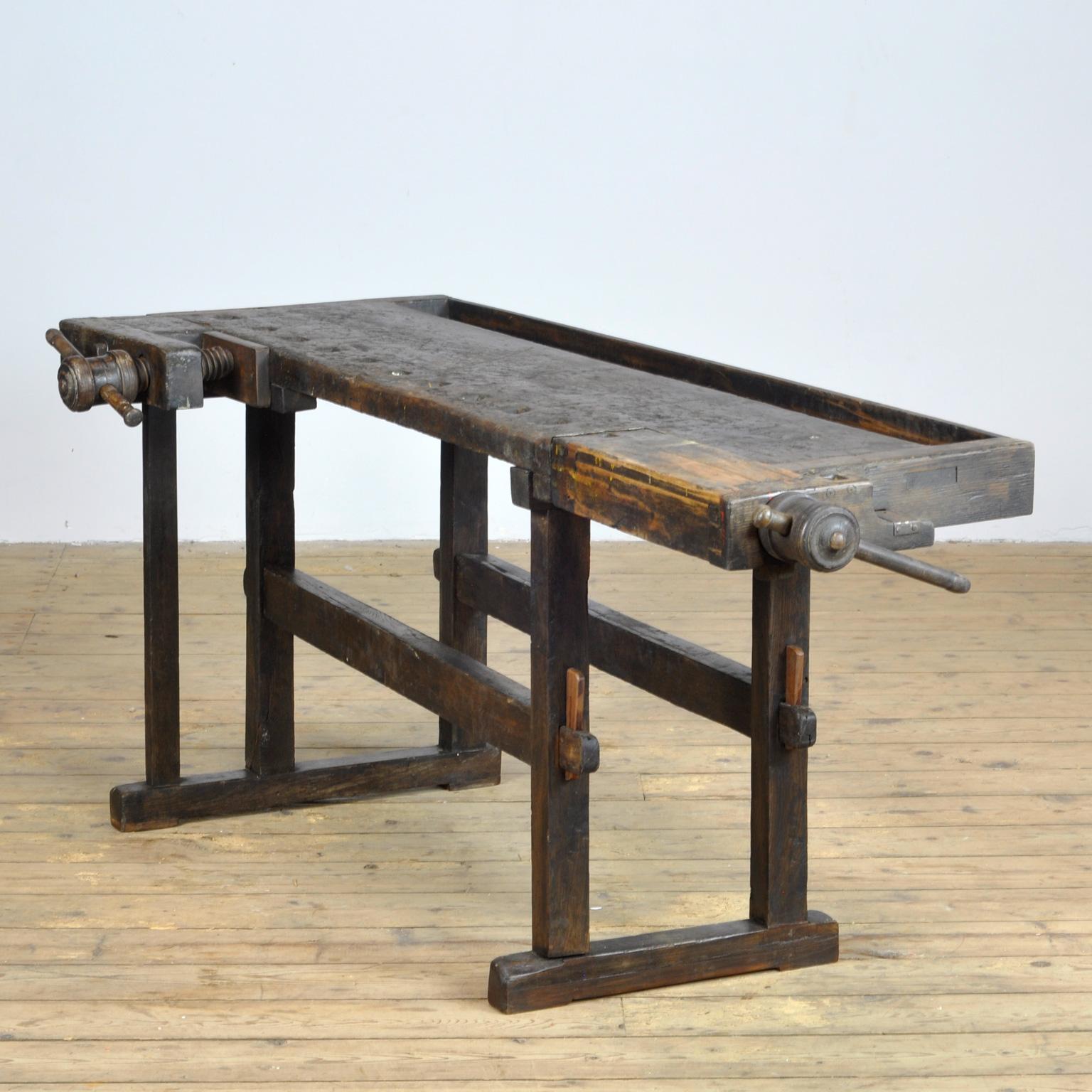 This antique workbench has two built-in wooden vices screws and a recessed tray where the carpenter would put his tools. It was manufactured, circa 1900. Made from oak. Beautiful patina after years of use. The workbench has been treated for