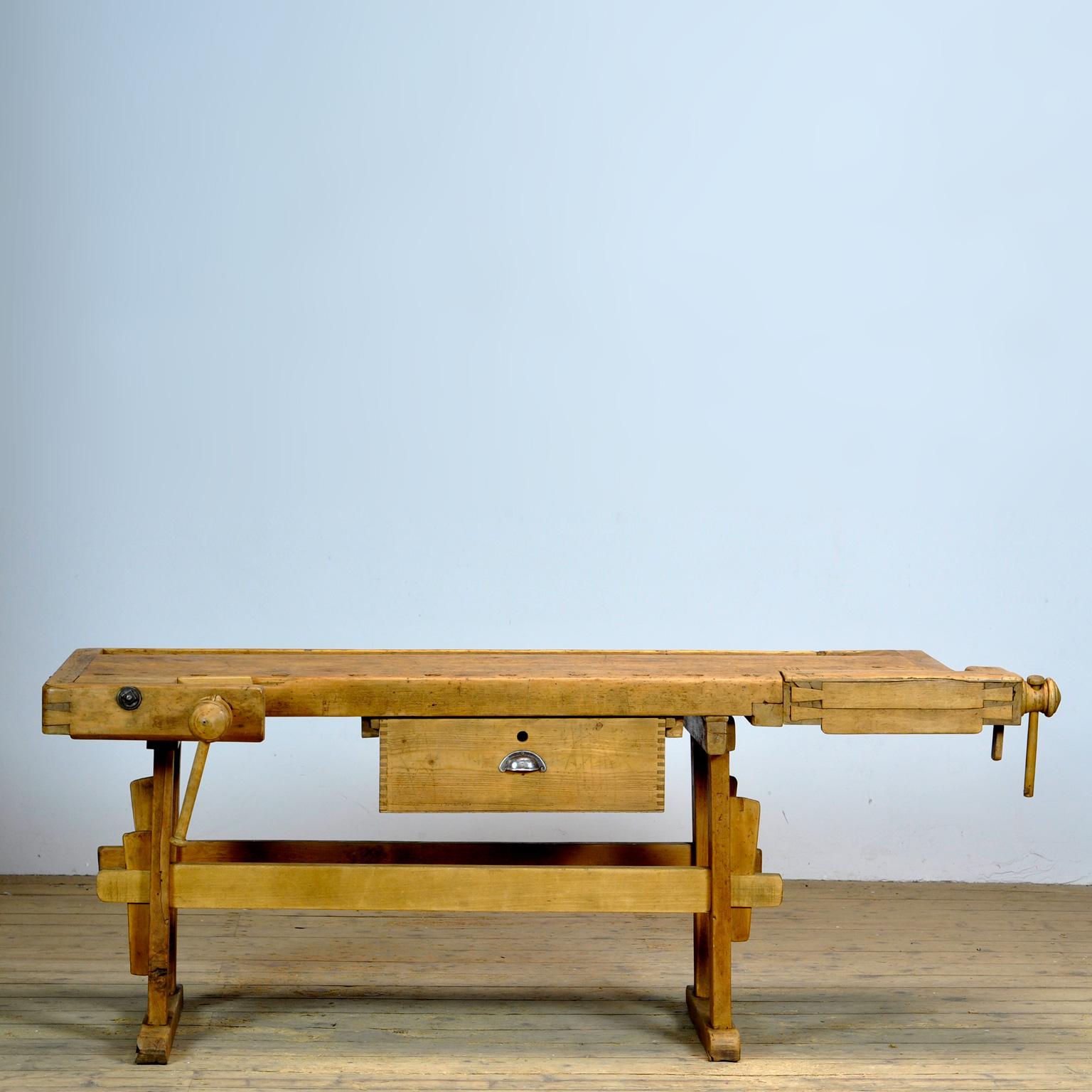 Cet établi ancien comporte deux étaux en bois intégrés, sculptés à la main, et un plateau encastré où le menuisier rangeait ses outils. Il a été fabriqué vers 1900. Fabriqué en chêne. Belle patine après des années d'utilisation intensive. L'établi a