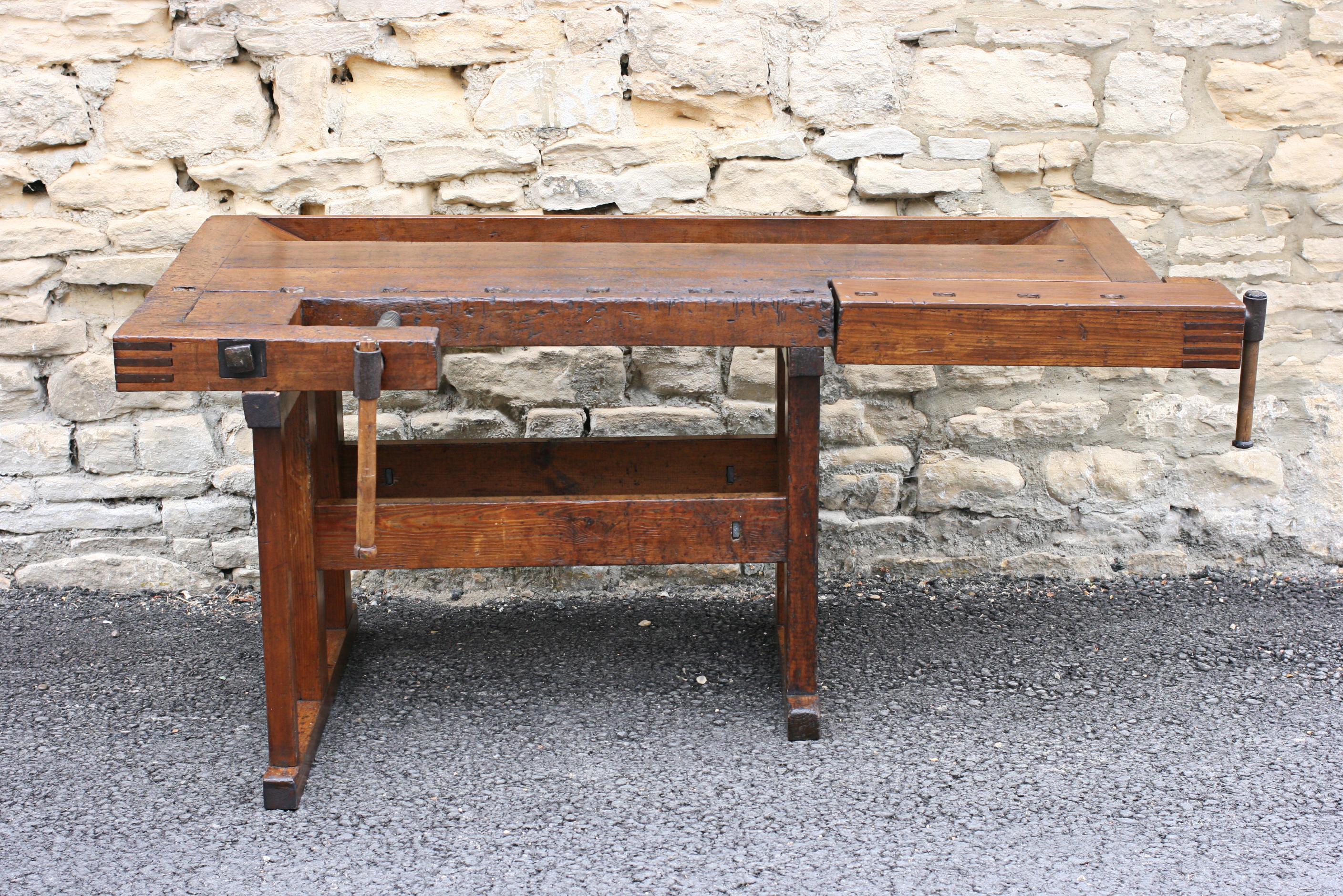 Antique carpenter's workbench.
A wonderful work bench with solid beechwood top and pine legs. The bench has two vices with metal threads, one on the front edge and the other on the right hand side. The top leading edge is drilled with square holes