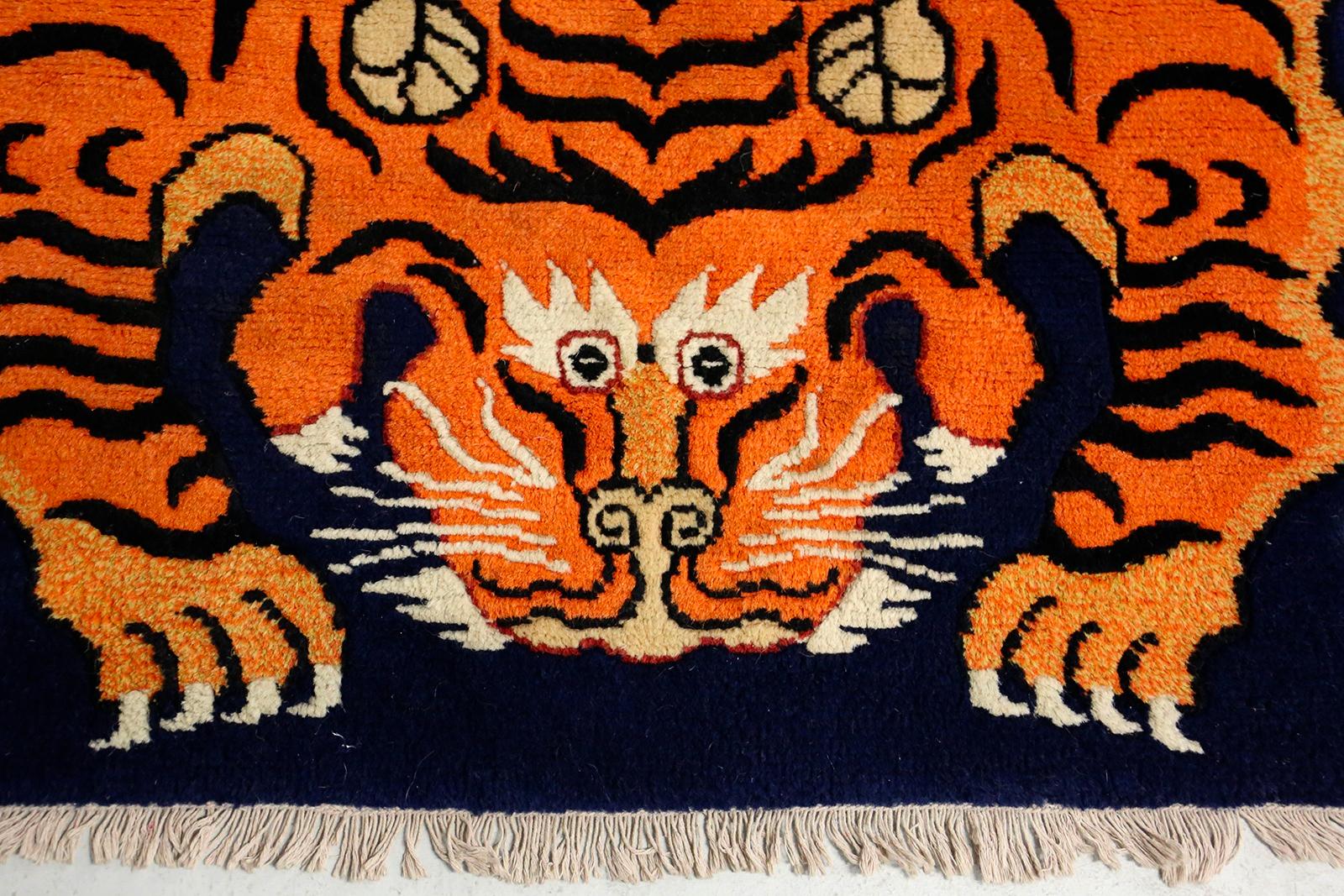 Beautiful and well colored Tibetan carpet in wool knotted by hand with cotton warp and in good condition, end of the 20th century. The symbol of the Tibetian Tiger: It was very common in antiquity and is the lord of all earthly creatures. It is